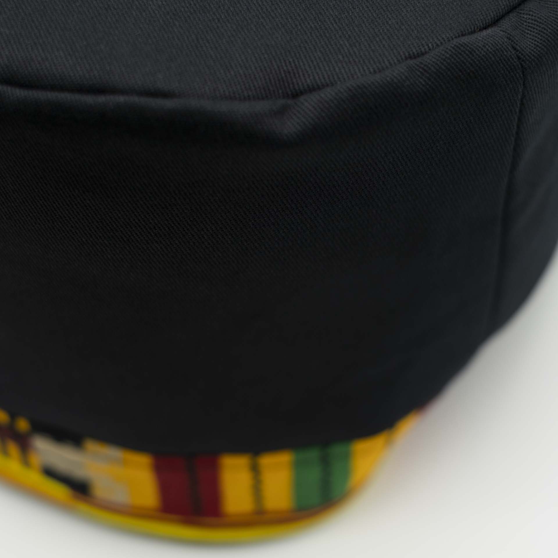 Chapeau Rasta traditionnel pour dreadlocks en coton noir accompagné d'un fin bandeau coloré en coton wax du Ghana sur le bas du chapeau doublure noir