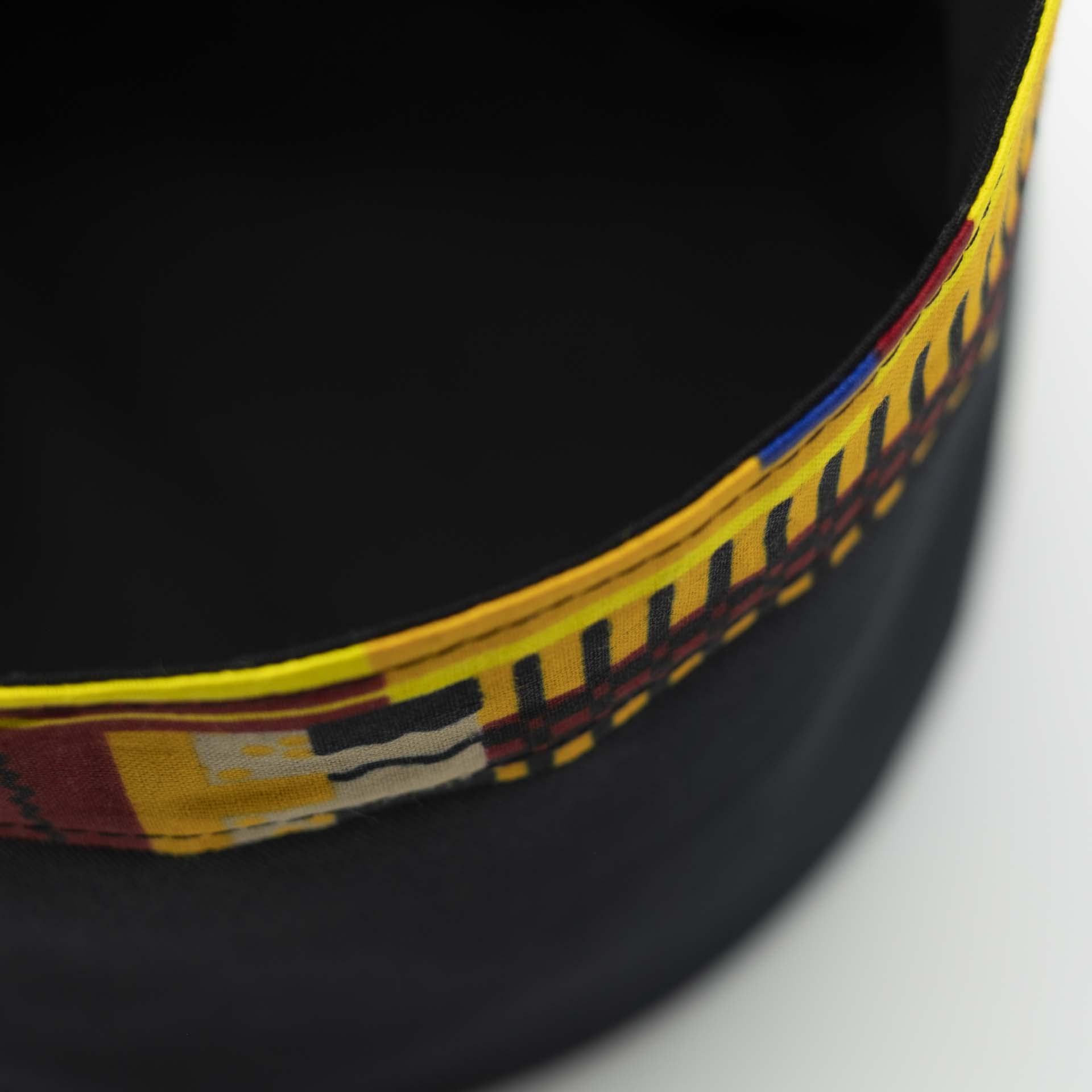 Chapeau Rasta traditionnel pour dreadlocks en coton noir accompagné d'un fin bandeau coloré en coton wax du Ghana sur le bas du chapeau doublure noir