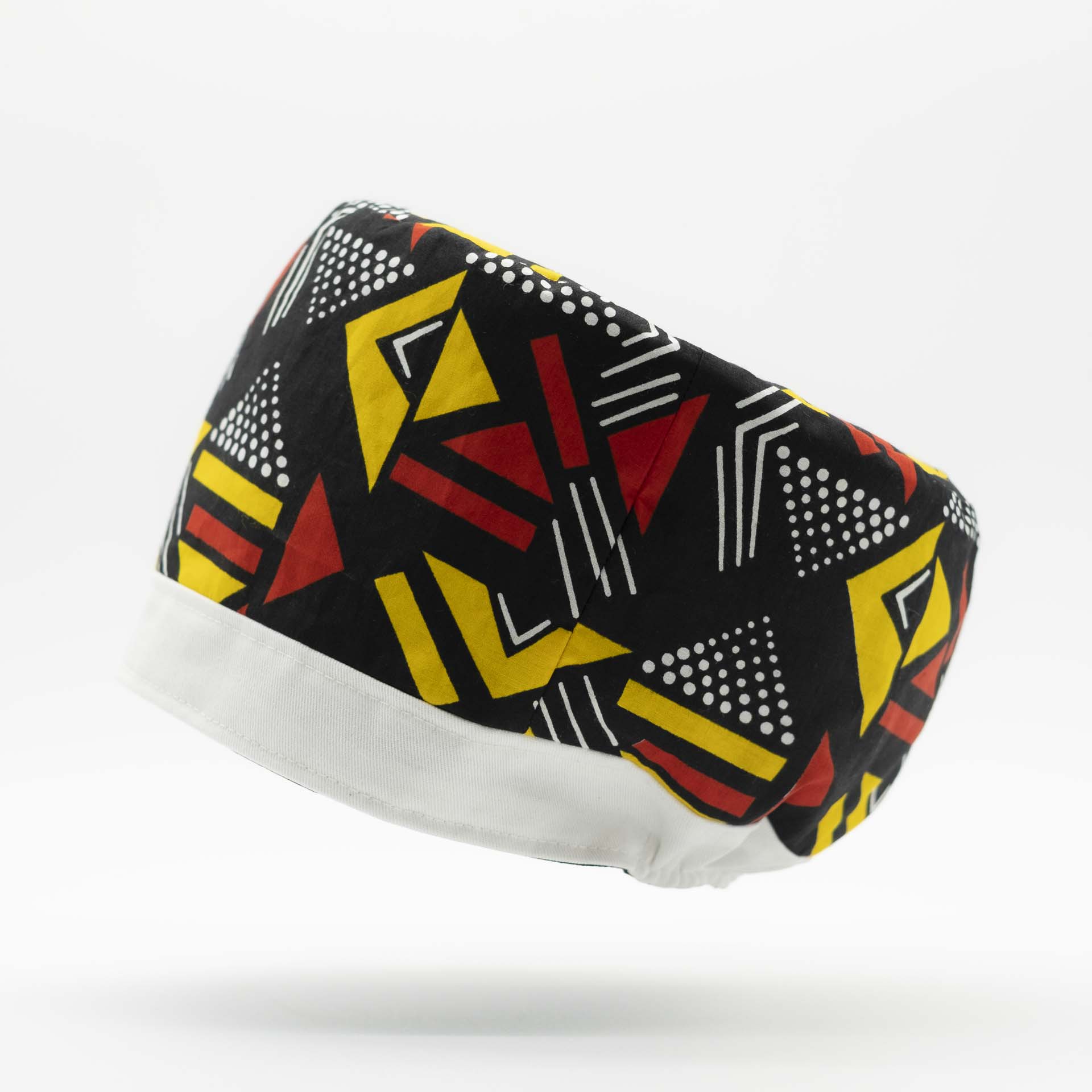 Traditional Rasta hat for dreadlocks in colored African wax with red and yellow geometric patterns on a black background with a white cotton headband at the bottom of the hat with black lining