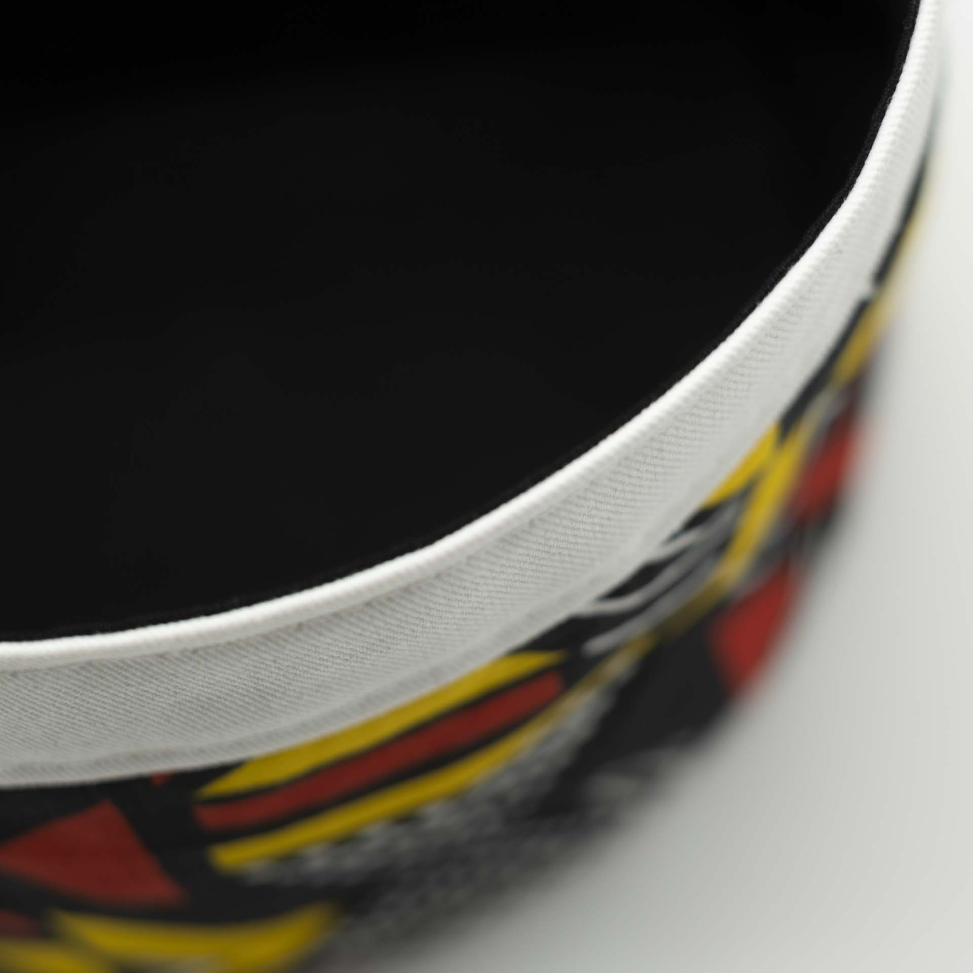 Traditional Rasta hat for dreadlocks in colored African wax with red and yellow geometric patterns on a black background with a white cotton headband at the bottom of the hat with black lining