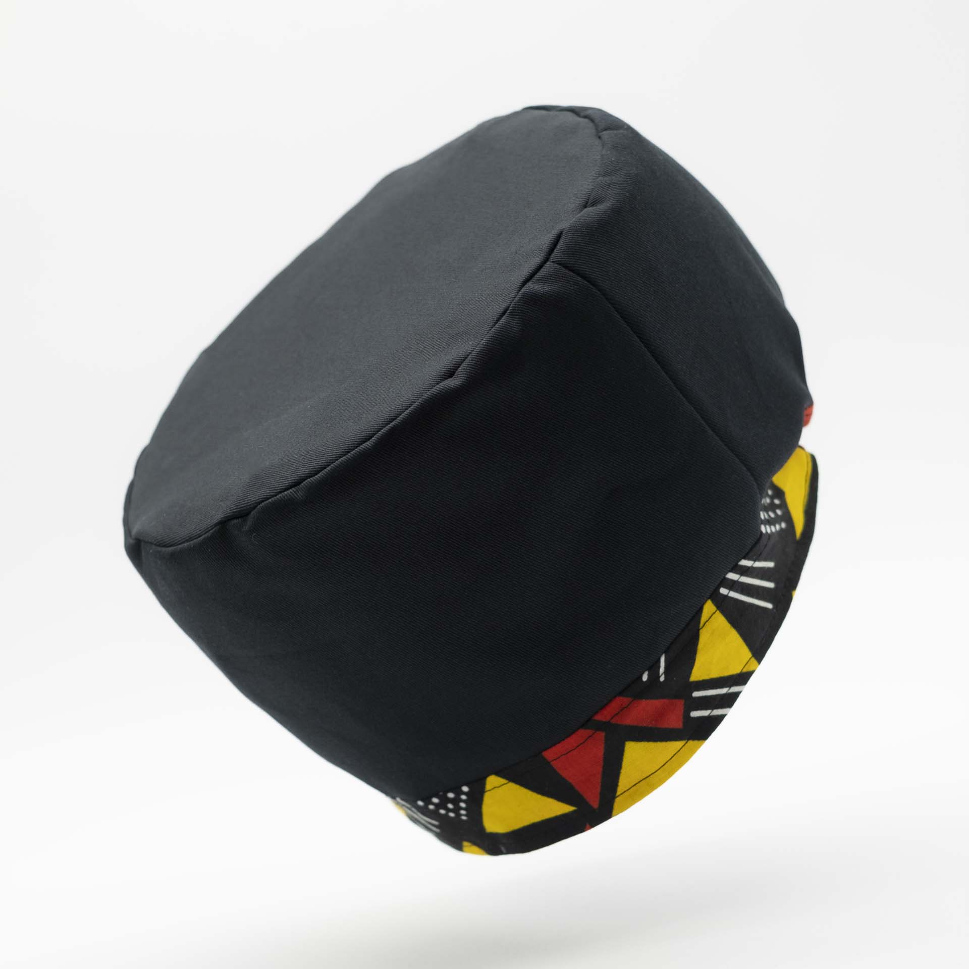 Traditional Rasta hat for dreadlocks in black cotton accompanied by a thin yellow and red colored headband in African wax cotton on the bottom of the hat with black lining