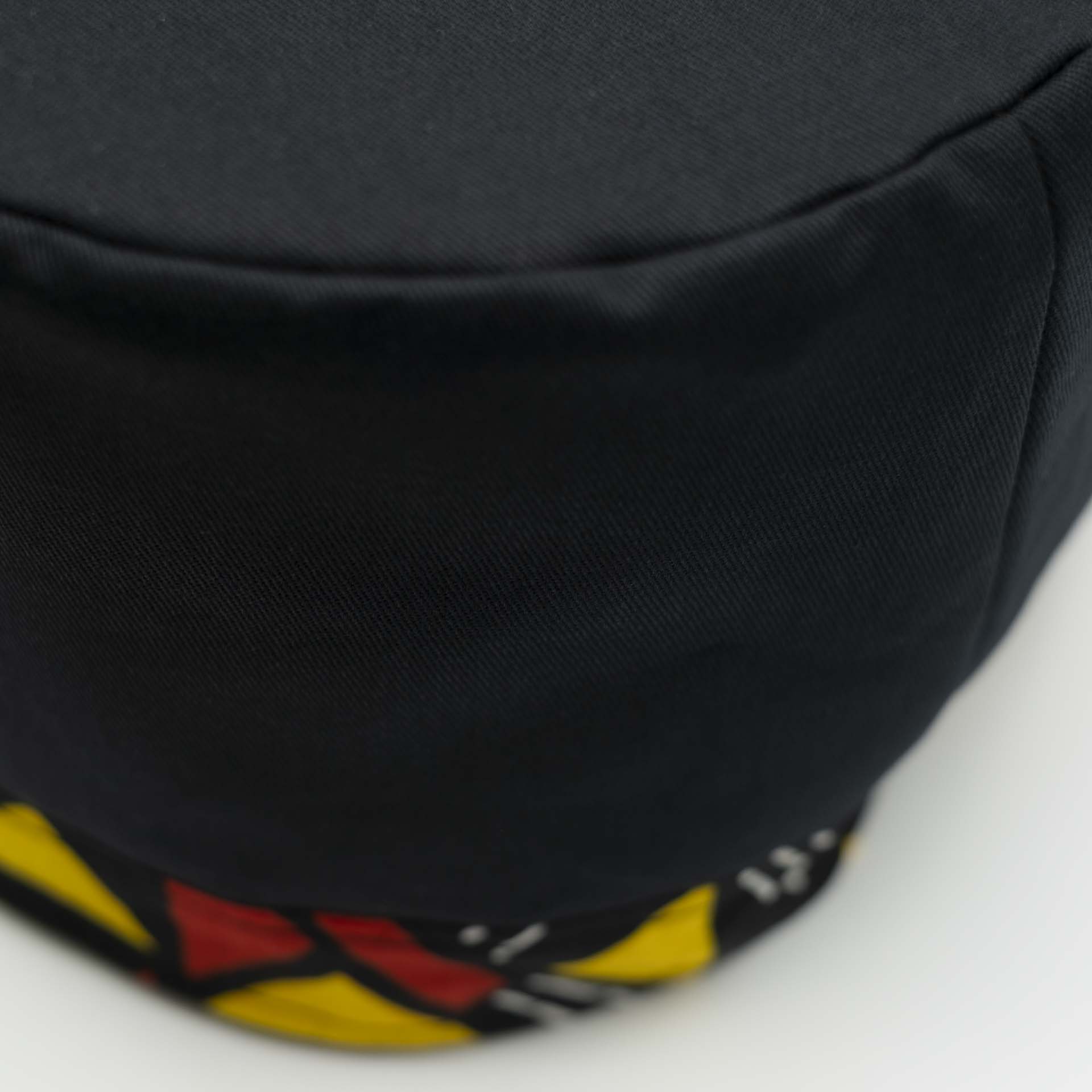 Chapeau Rasta traditionnel pour dreadlocks en coton noir accompagné d'un fin bandeau coloré jaune et rouge en coton wax Africain sur le bas du chapeau doublure noir