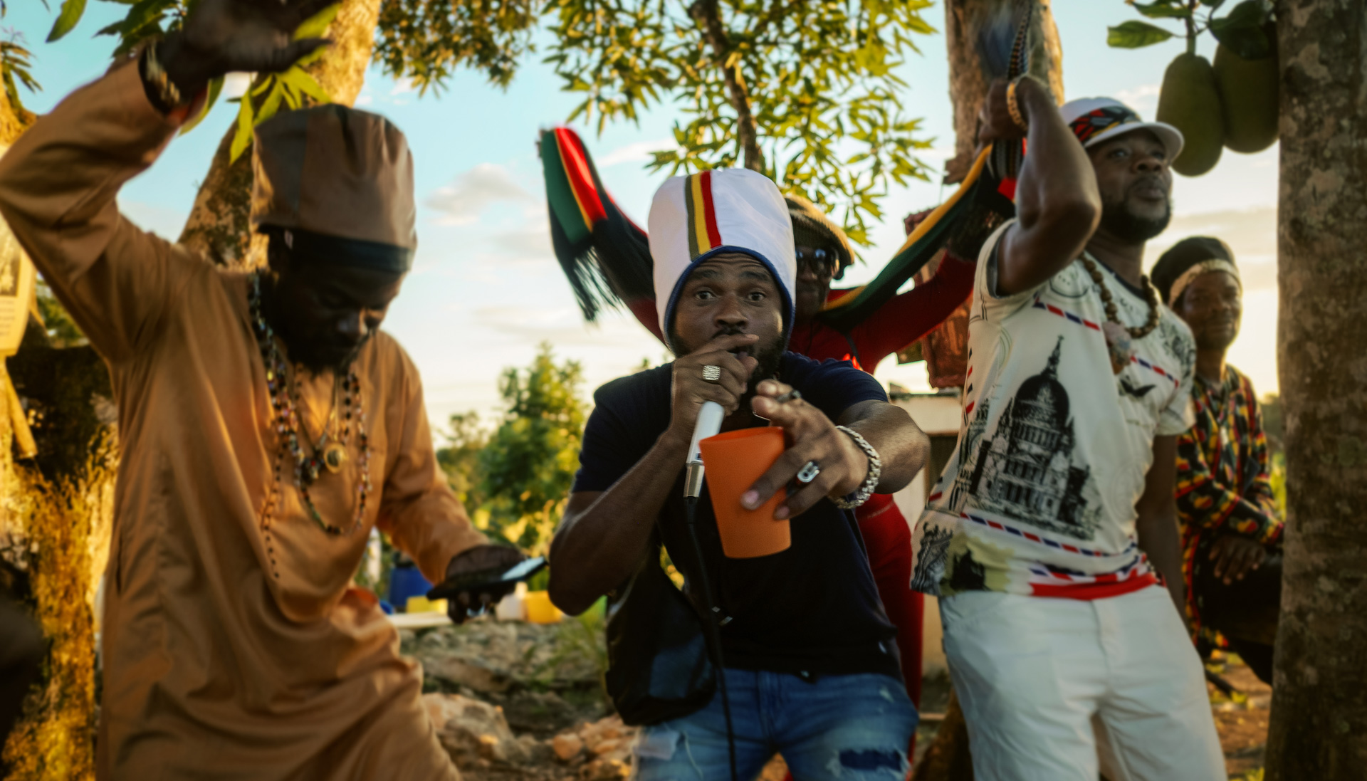 Ishadrock Jamaican artist performing in the middle of the hills with a big white dreadlocks hat striped with Ethiopian colors