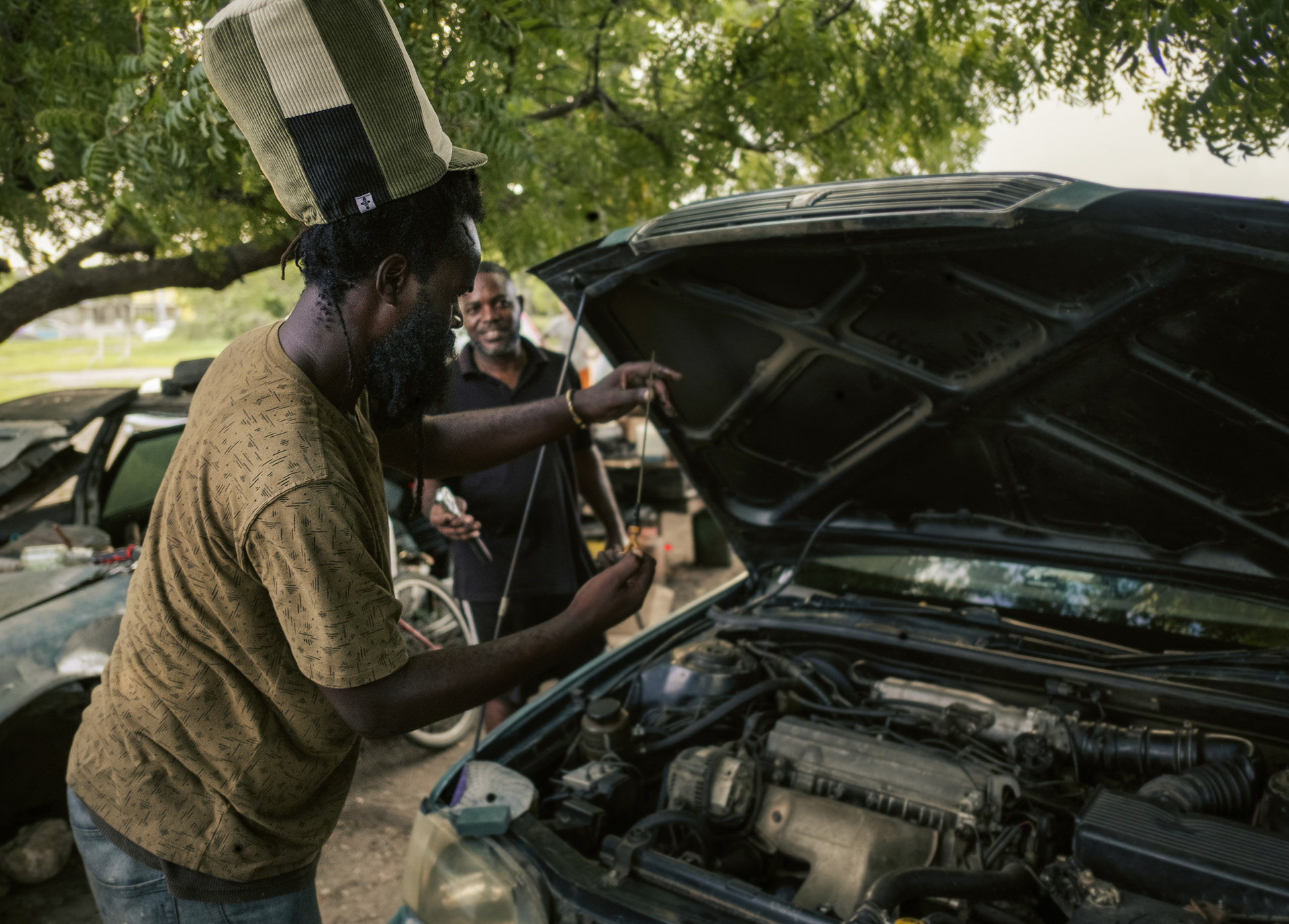 Mechanic Rastaman working on a car and wearing a big dreadlocks hat