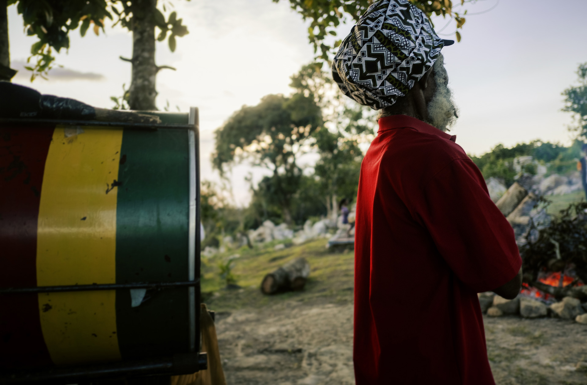 Jamaican old Rastaman in front of a big African congas wearing an ethnic wax dreadlocks hat