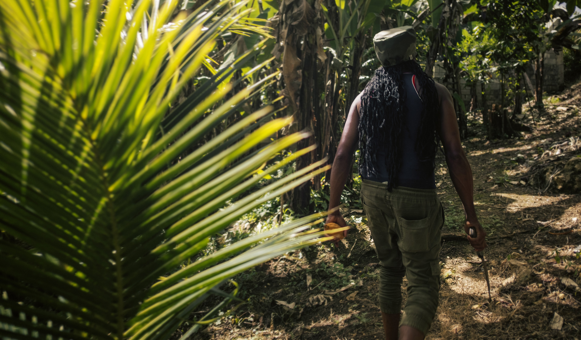 A rastaman in the bush with his machette and his camo dreadlocks hat