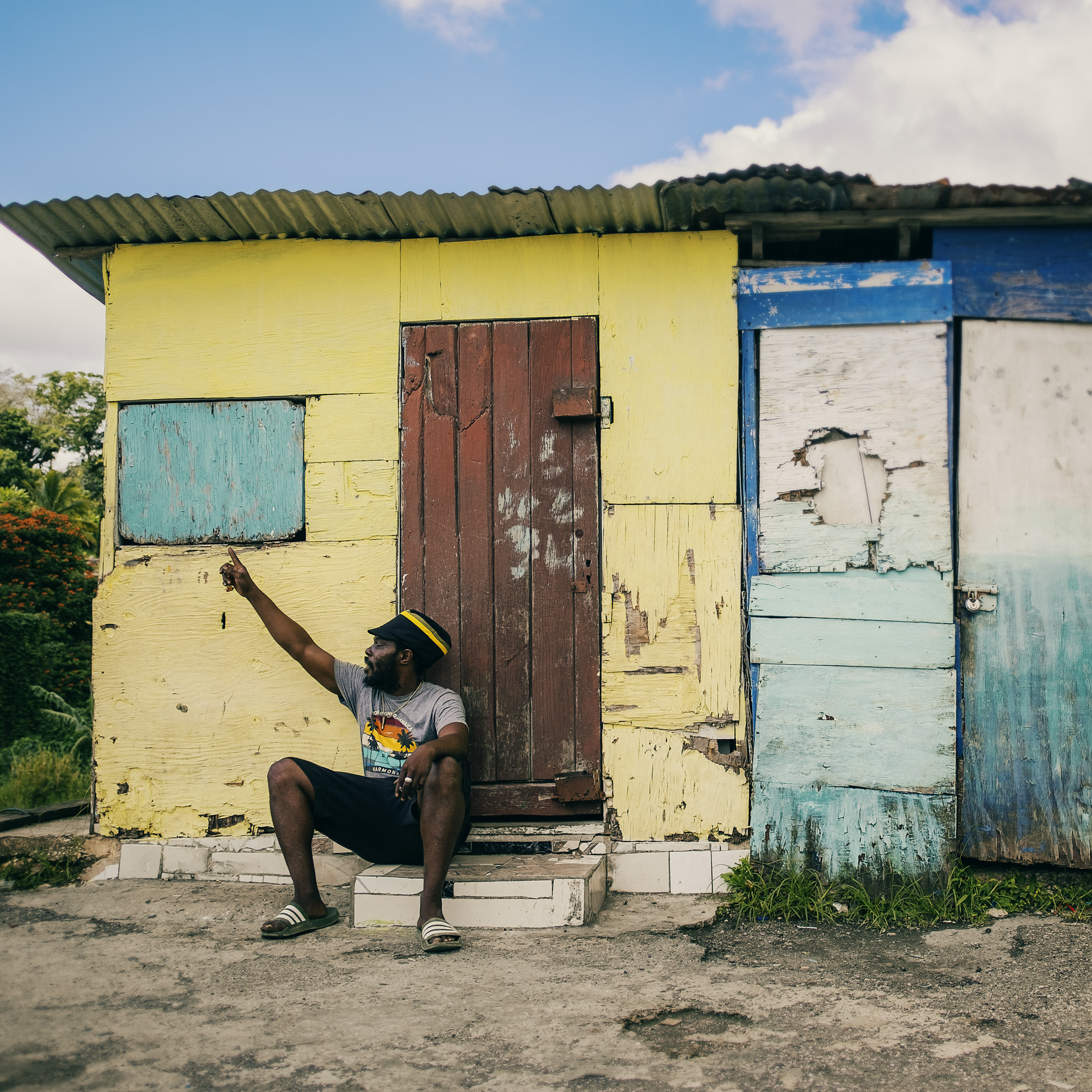 Rastaman in front of a small shop proudly wearing a Jamaican color dreadlocks hat