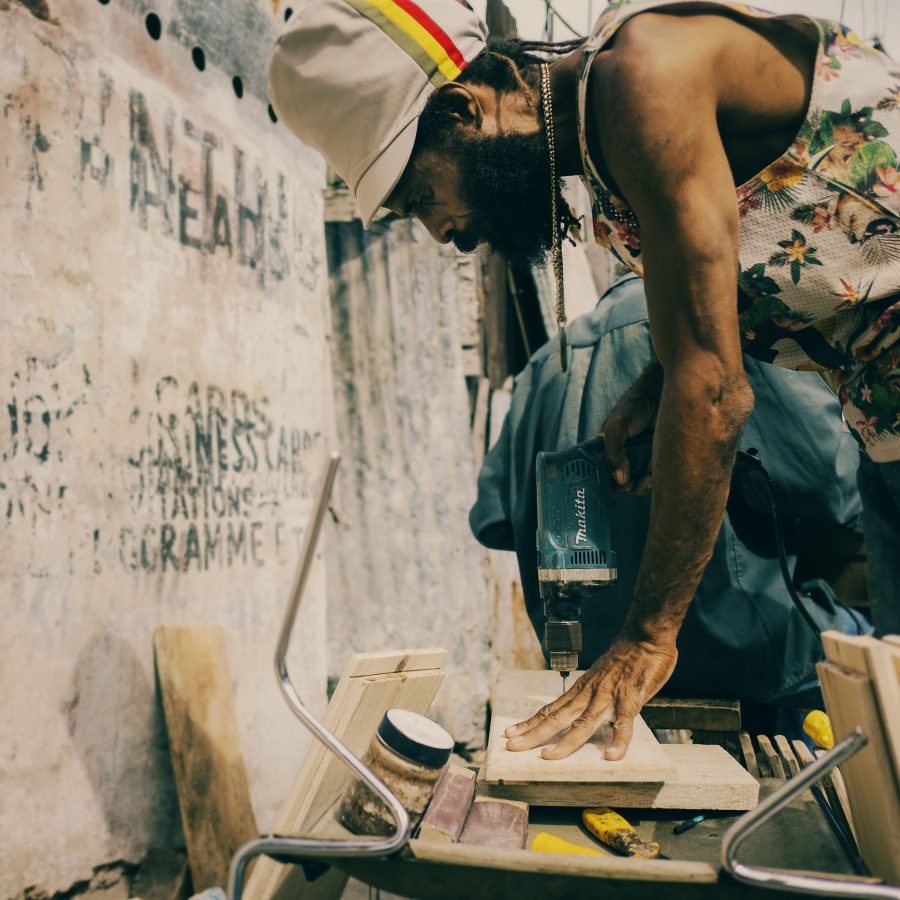 Jamaican Rasta carpenter working in the street with a beige and Ethiopian stripes dreadlocks tam