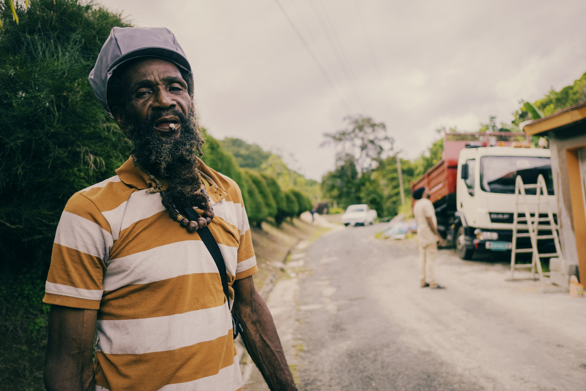 Jamaican Rasta Clifford wearing grey dreadlocks cap and smoking a spliff