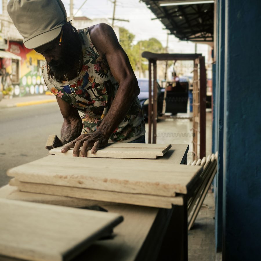 Jamaican Rasta carpenter working in the street with a beige and Ethiopian stripes dreadlocks tam