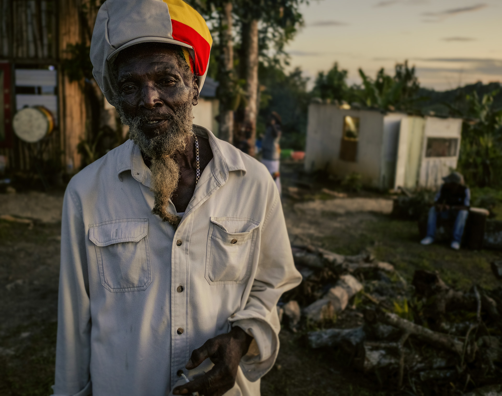 Rastaman in the Jamaican hills with a beige dreadlocks cap striped in red gold and green