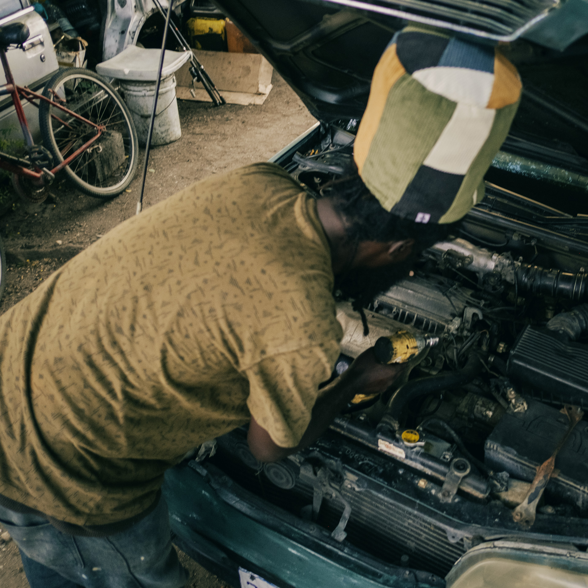 Mechanic Rastaman working on a car and wearing a big dreadlocks hat