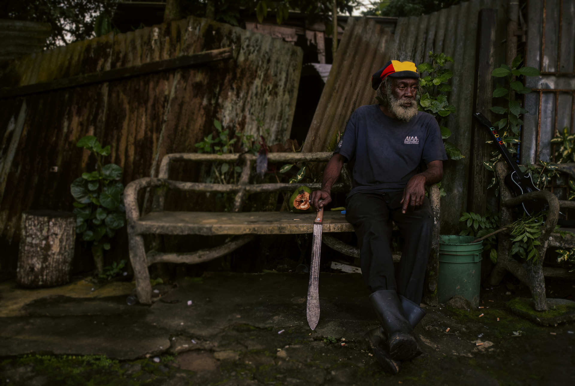 Old Rastaman with dreadlocks cap sitting on a bench