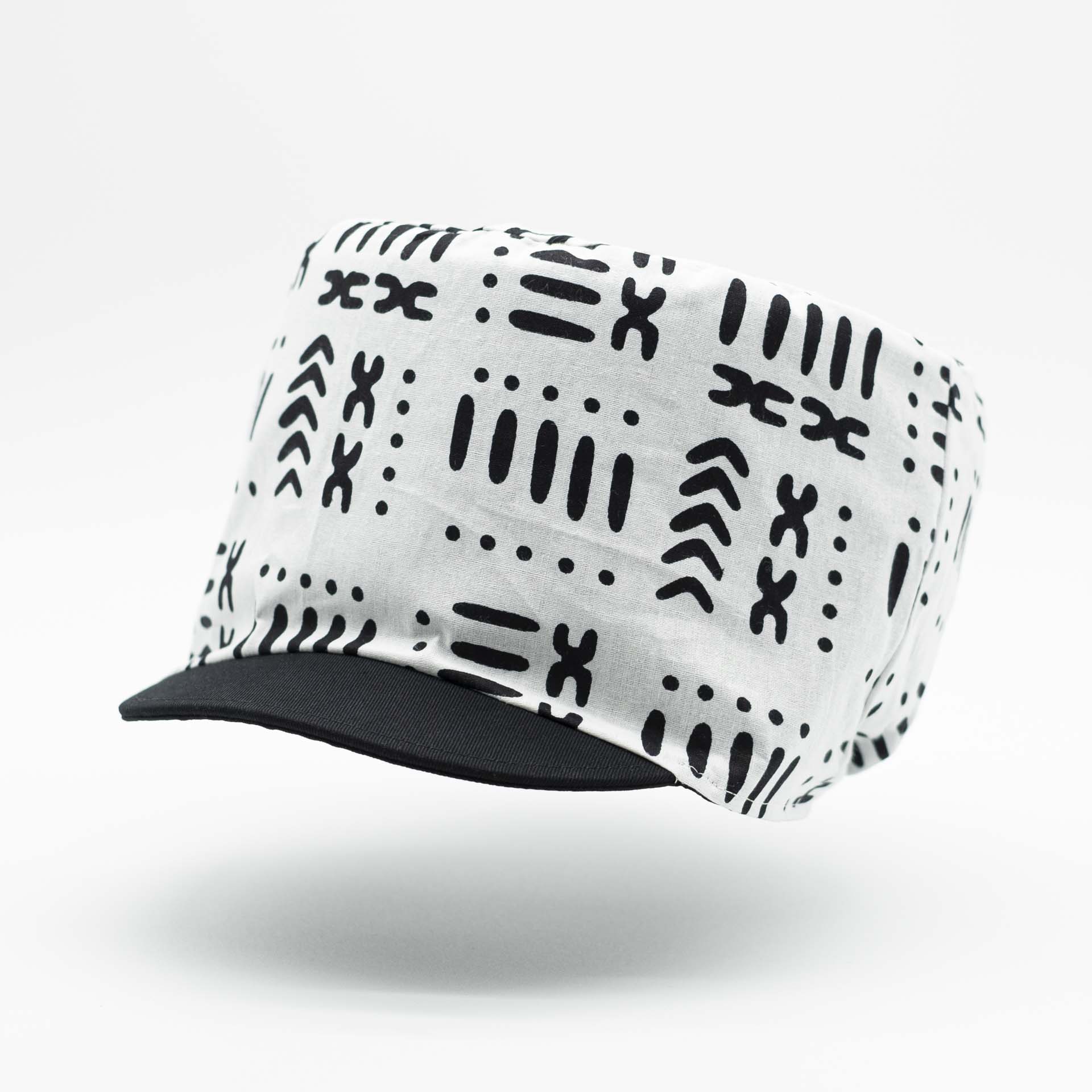 Rasta dreadlocks hat in light wax fabric with black African ethnic patterns on a white background with black lining