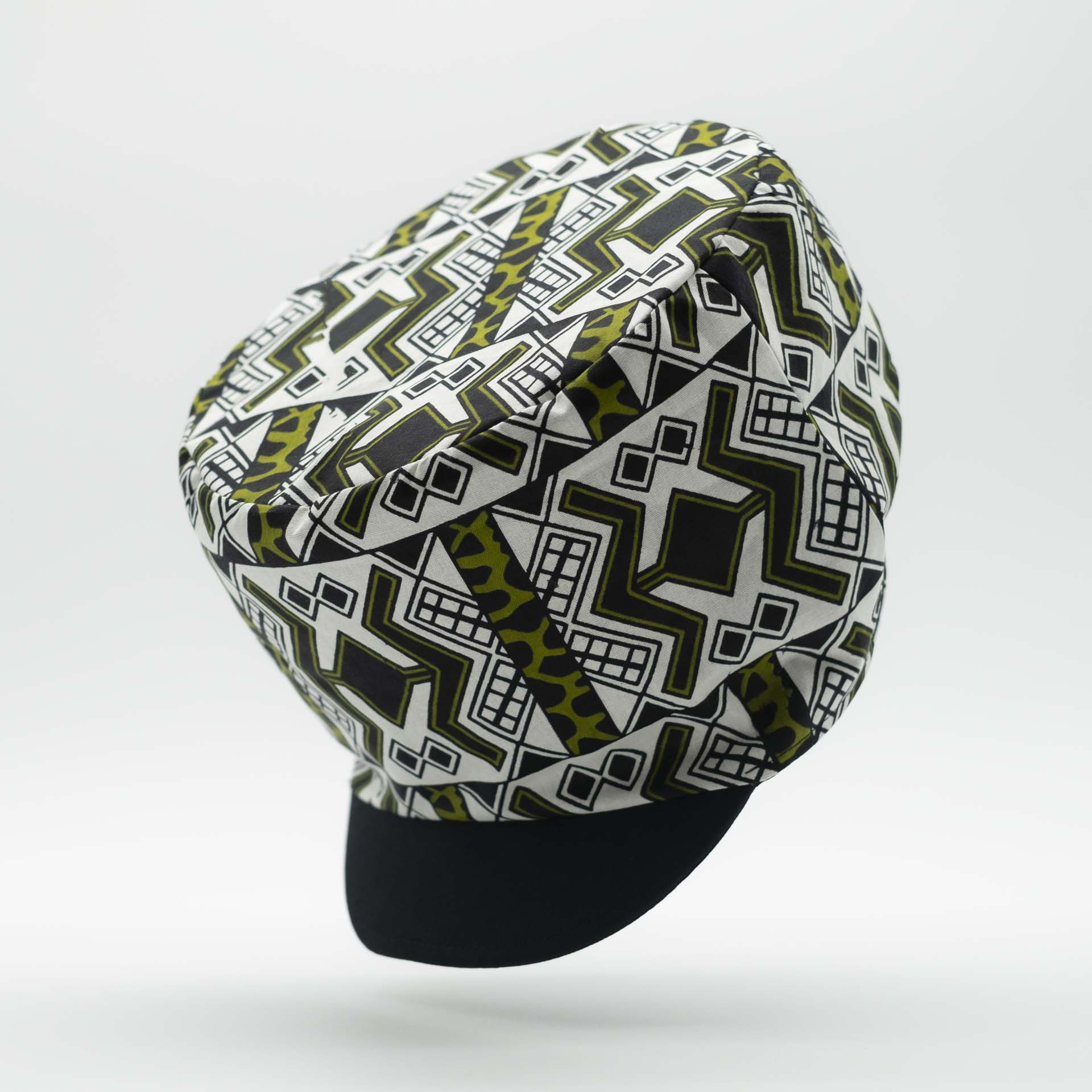 Rasta hat with black visor in light wax fabric with white and green ethnic patterns, black lining