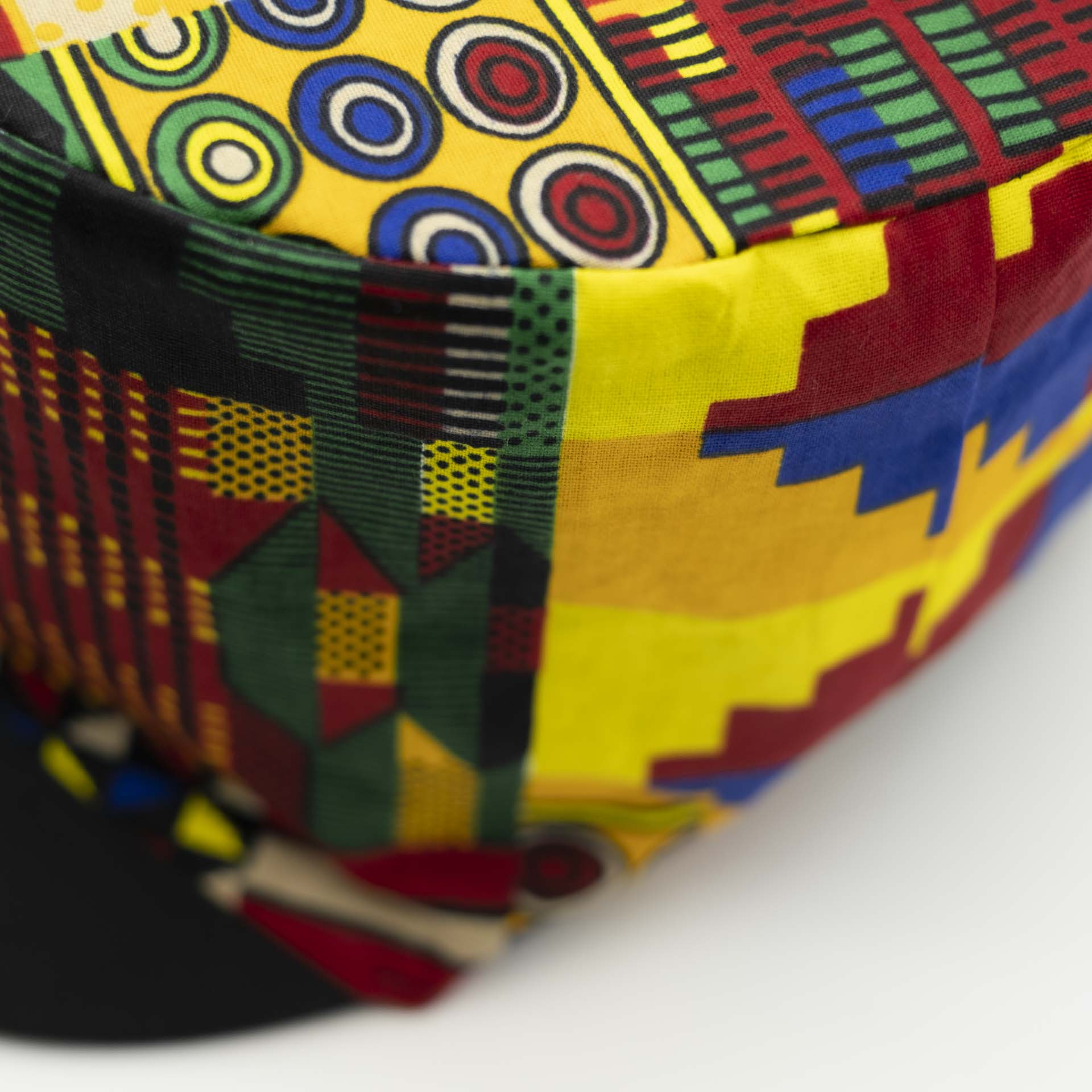 Rasta dreadlocks hat with black visor in light wax fabric with colorful African patterns black lining