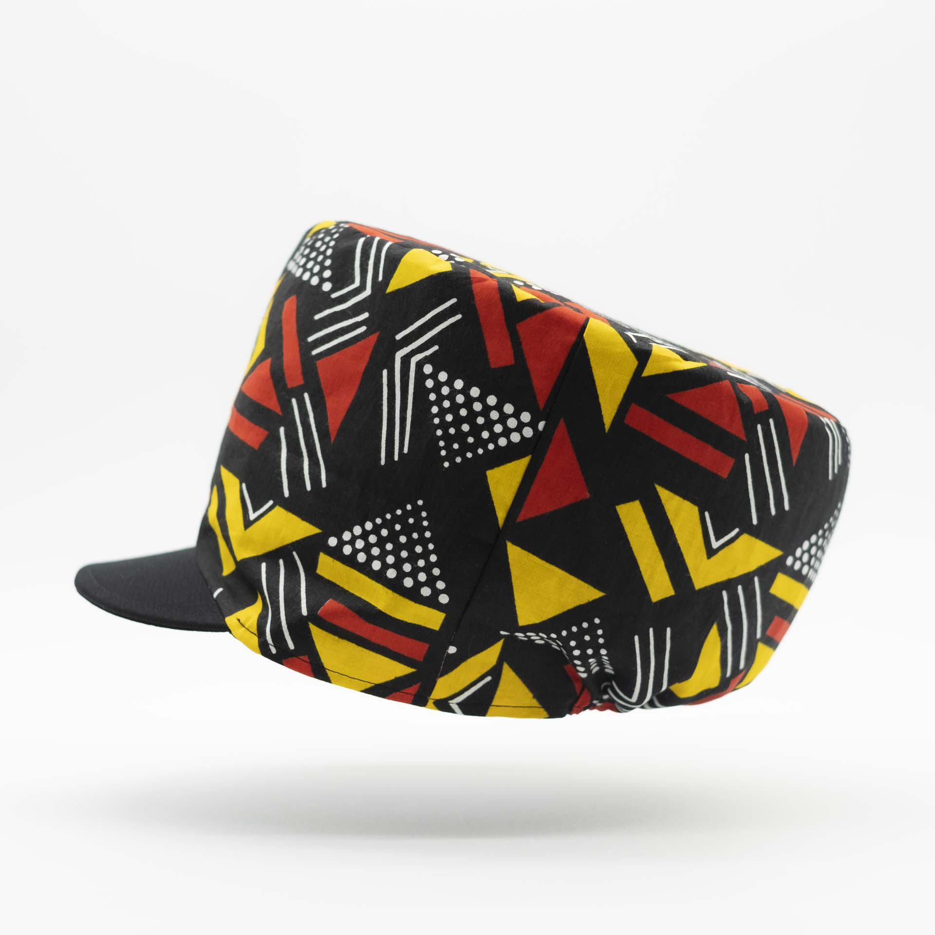 Rasta dreadlocks hat with black visor in light wax fabric with colorful red and yellow geometric patterns, black lining