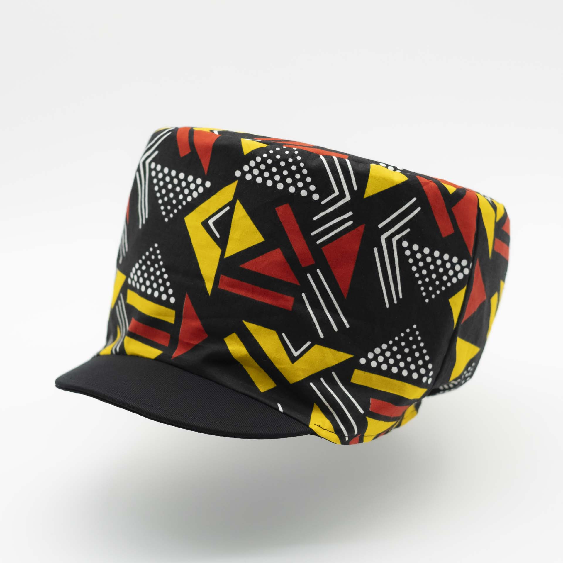 Rasta dreadlocks hat with black visor in light wax fabric with colorful red and yellow geometric patterns, black lining