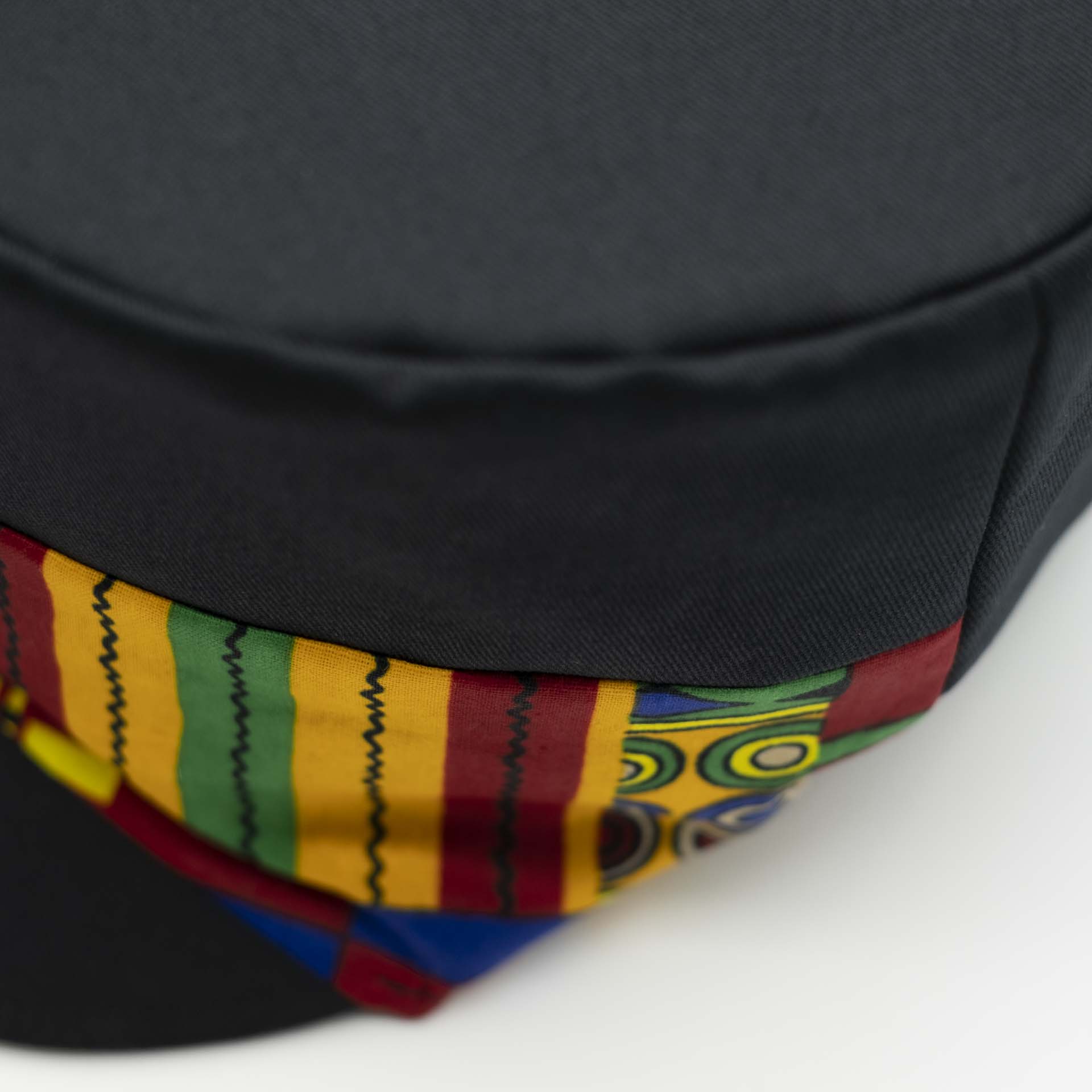 Rasta cap with dreadlocks in black cotton with a front pant in colored wax patterns from Ghana, black lining