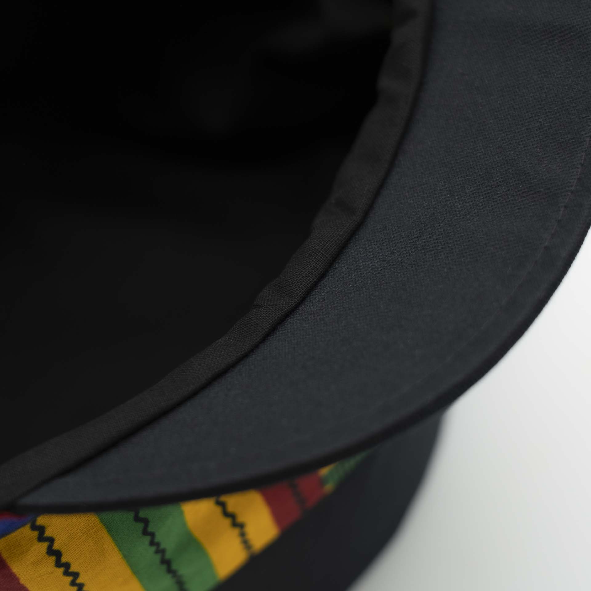 Rasta cap with dreadlocks in black cotton with a front pant in colored wax patterns from Ghana, black lining