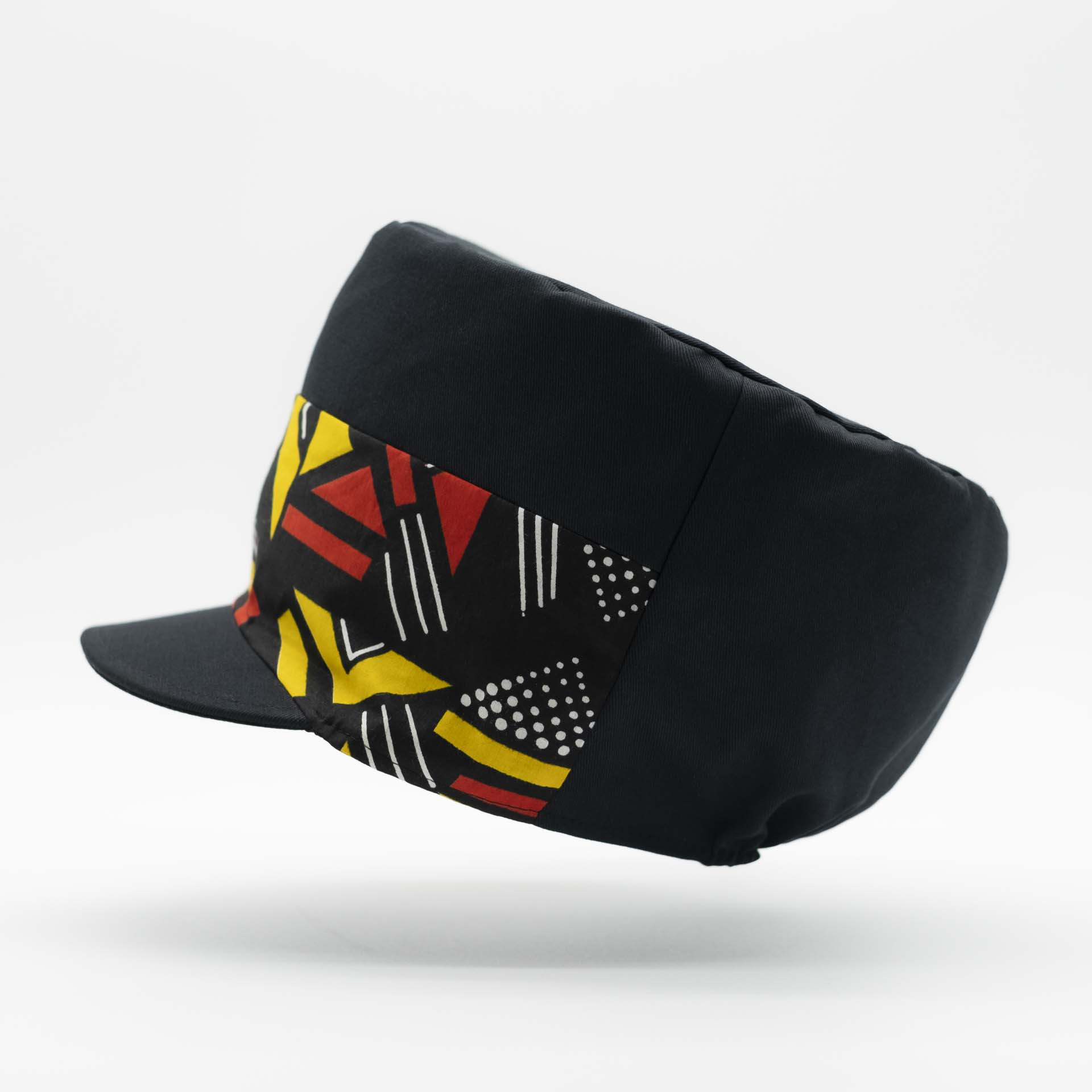 Rasta cap with dreadlocks in black cotton with a front pant facing in wax with yellow and red geometric patterns, black lining