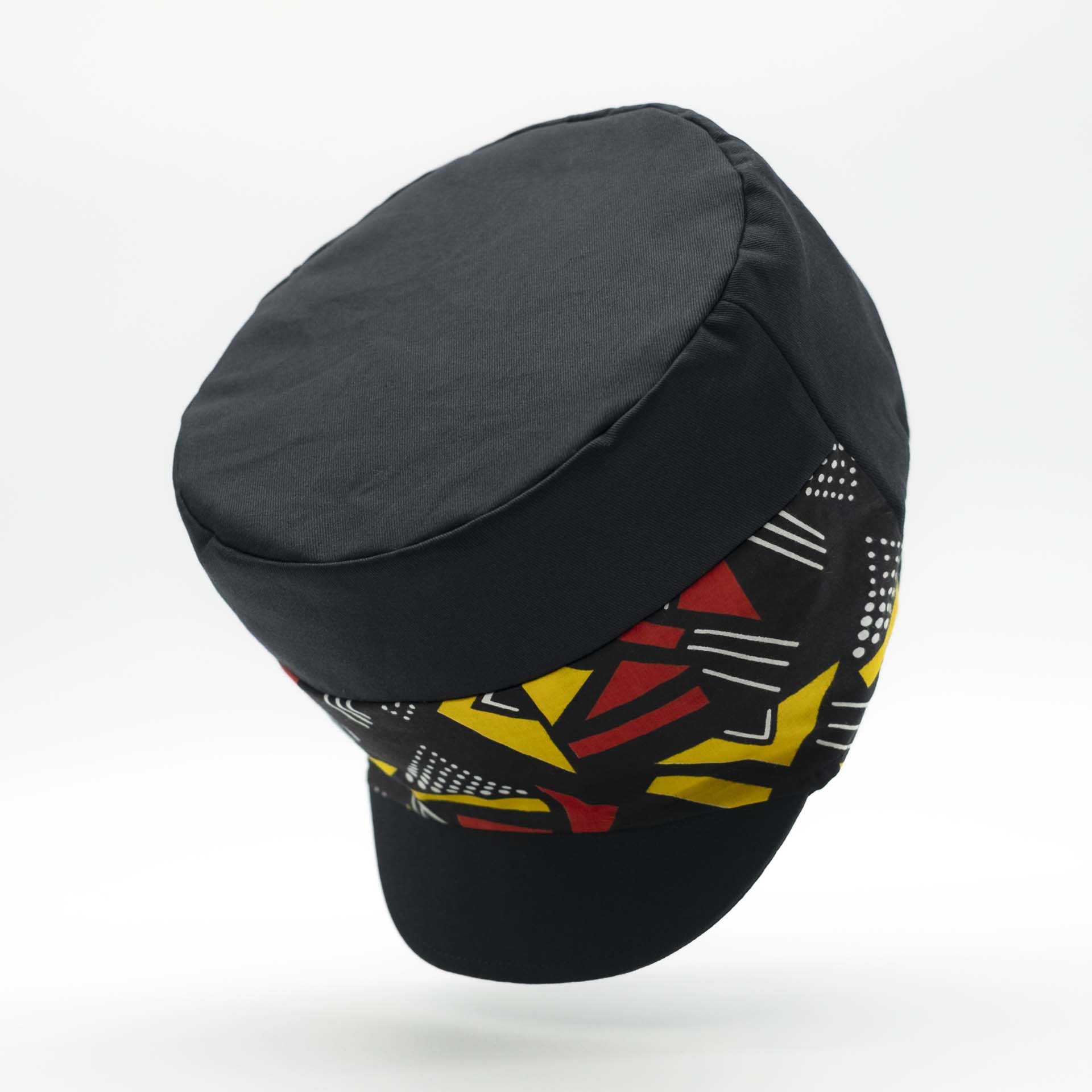 Rasta cap with dreadlocks in black cotton with a front pant facing in wax with yellow and red geometric patterns, black lining