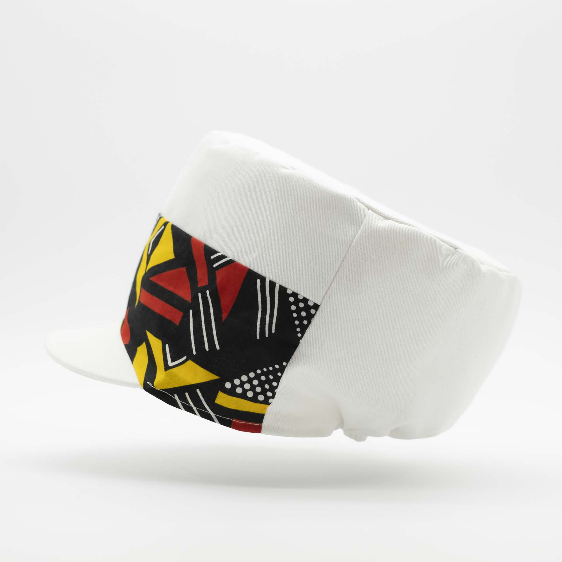 Rasta cap with dreadlocks in white cotton with a front pant facing in yellow and red geometric pattern wax with white lining