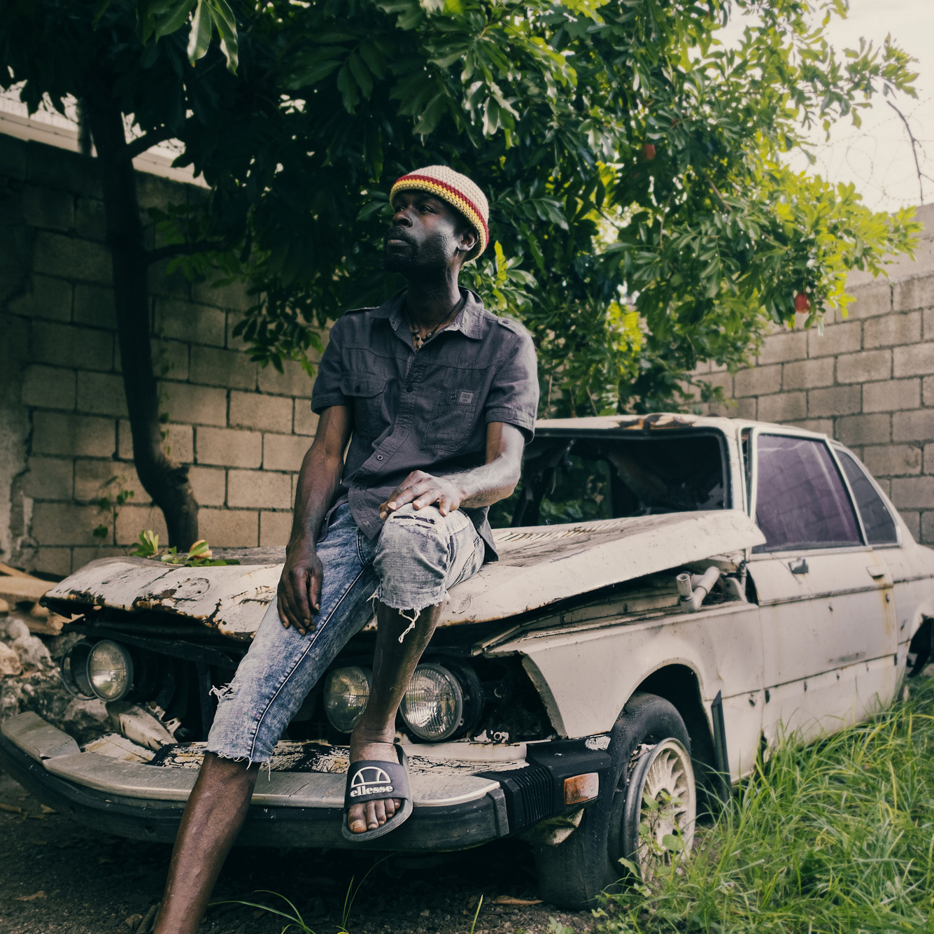Carron Mc Gibbon devant une vielle voiture posant pour Dreadlocks Nation