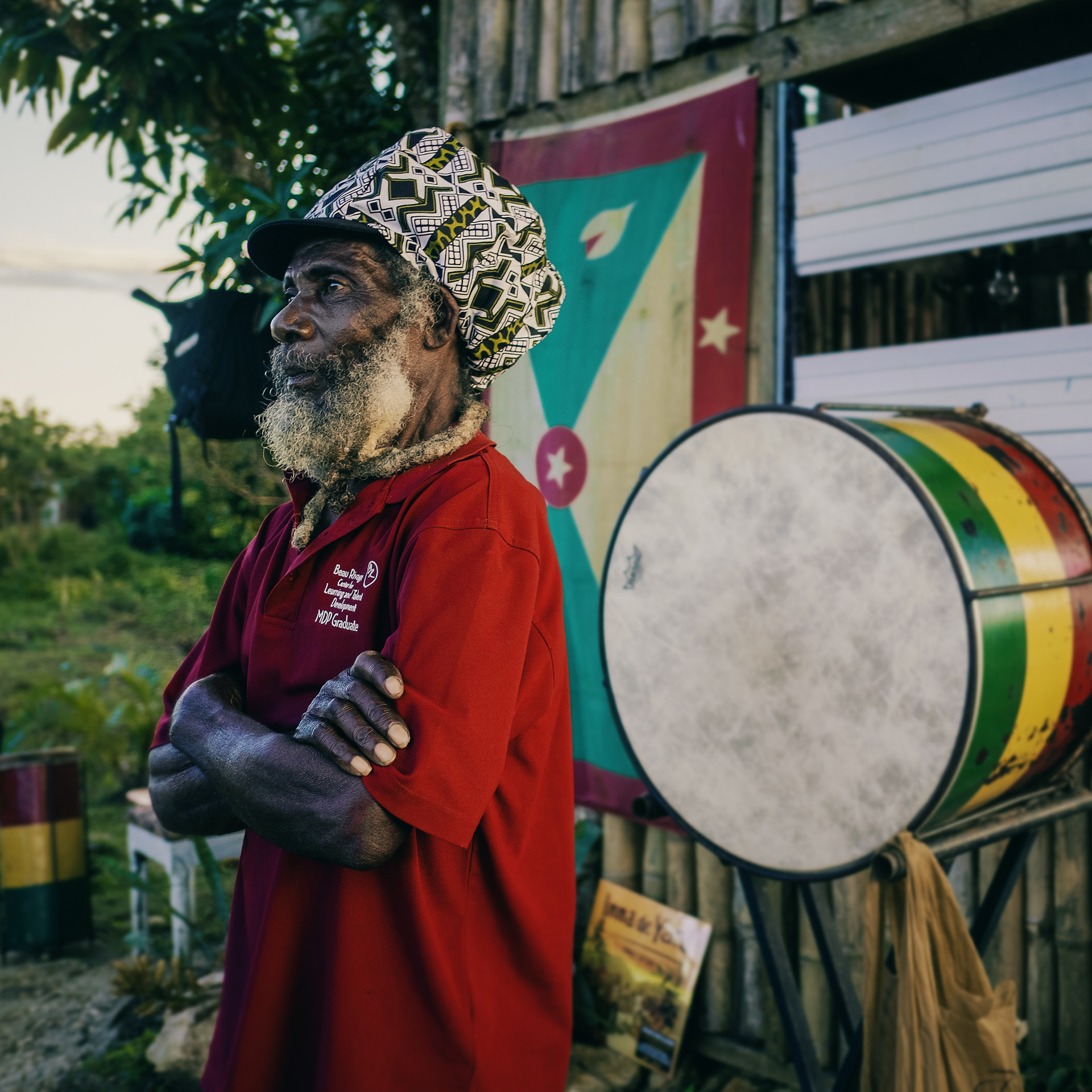 Jamaican old Rastaman in front of a big African congas wearing an ethnic wax dreadlocks hat