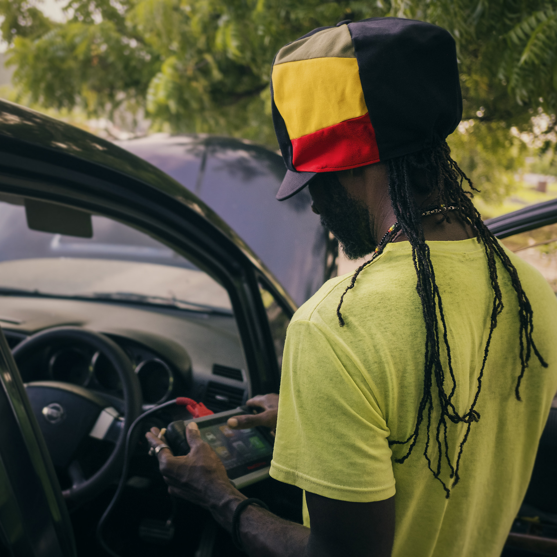 Rastaman fixing a car in Kingston with a dreadlocks hat from the Rocksteady collection