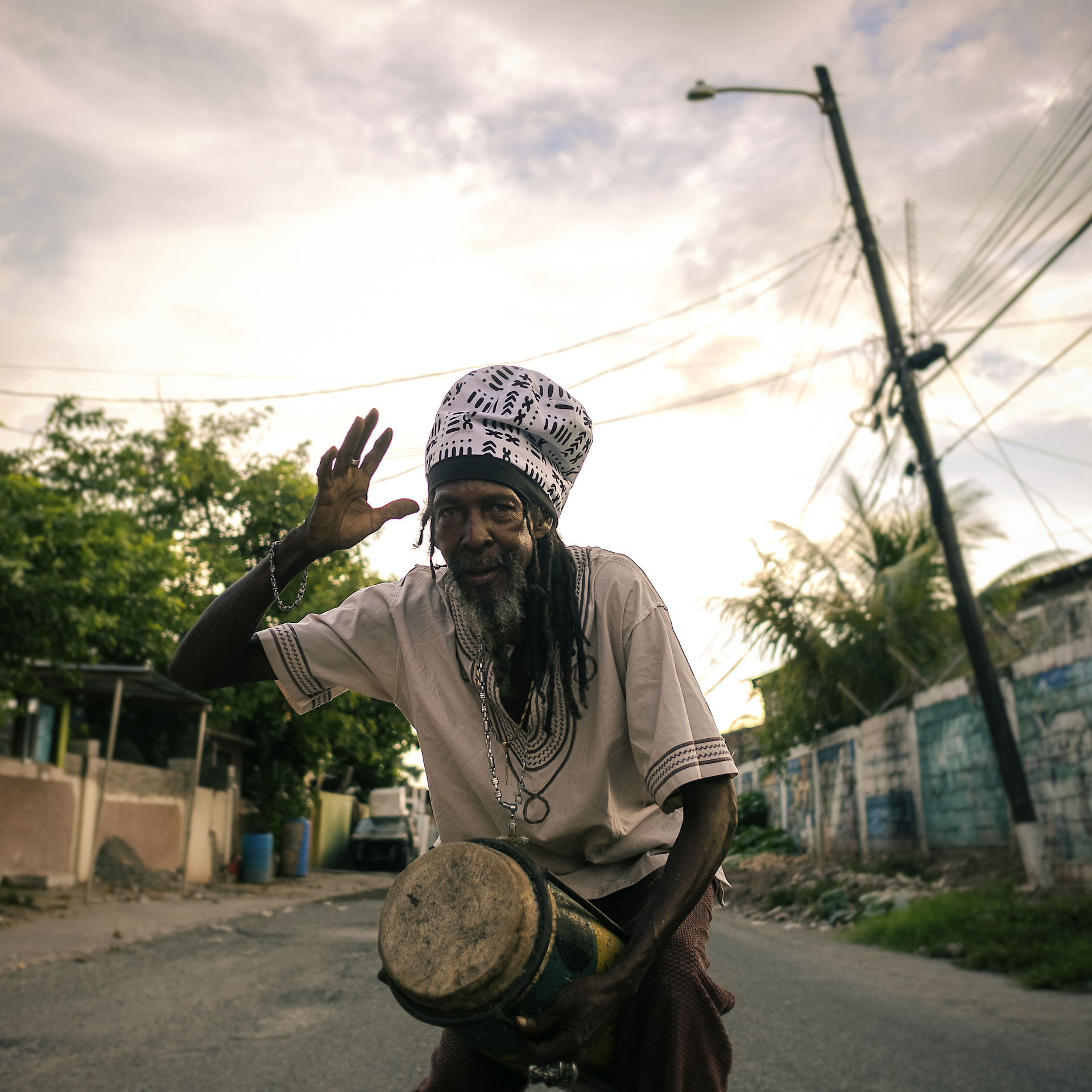 Jamaican drum Artist performing Nyabinghi in the middle of Kingston street with a black and white dreadlocks crown without visor