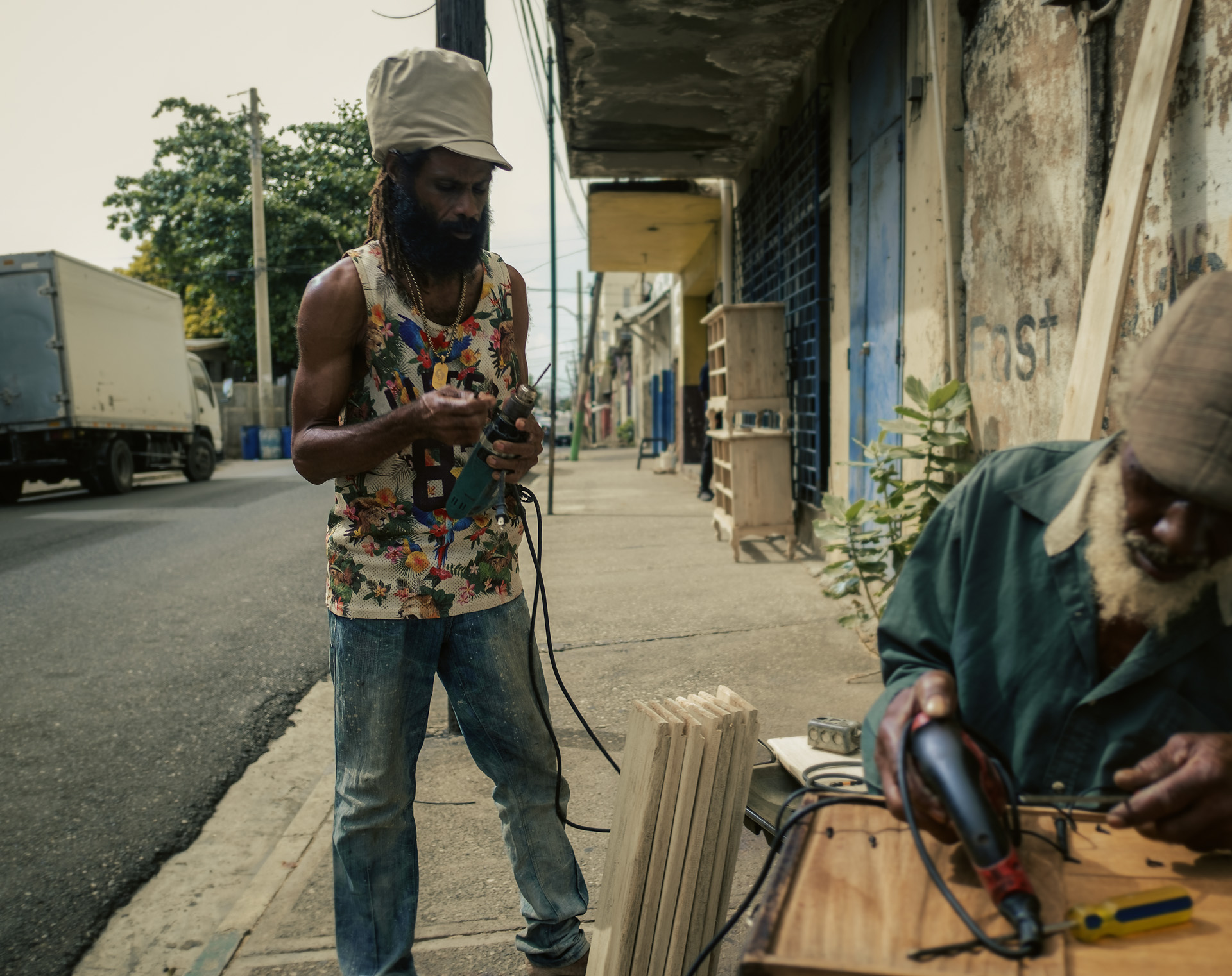 Menuisier Jamaïcain travaillant dans un rue de Kingston avec son chapeau Rasta beige