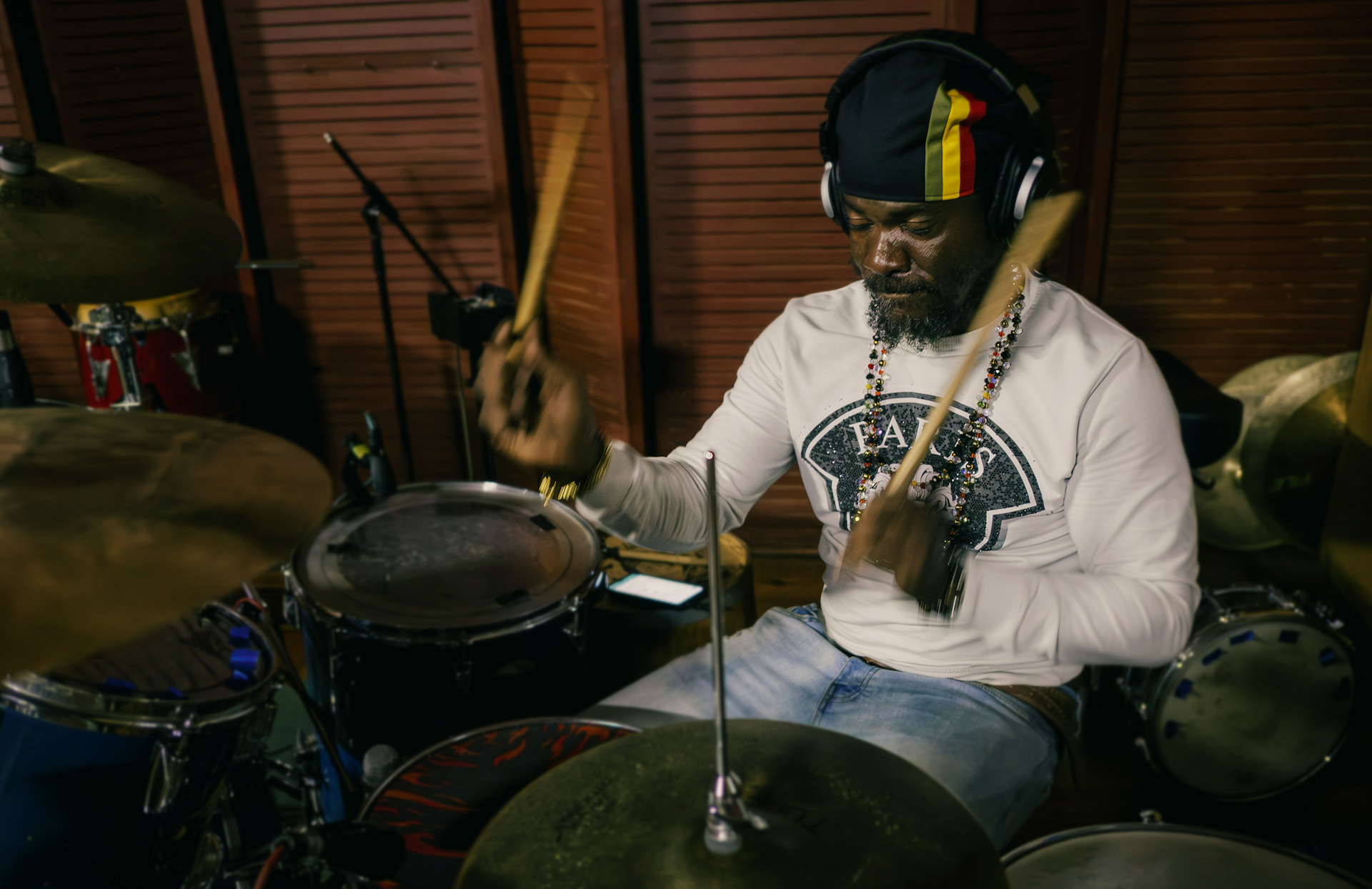 Kush McAnuff playing drum at Tuff Gong studio Jamaica with a dreadlocks nation Rasta hat black with stripes red gold and green