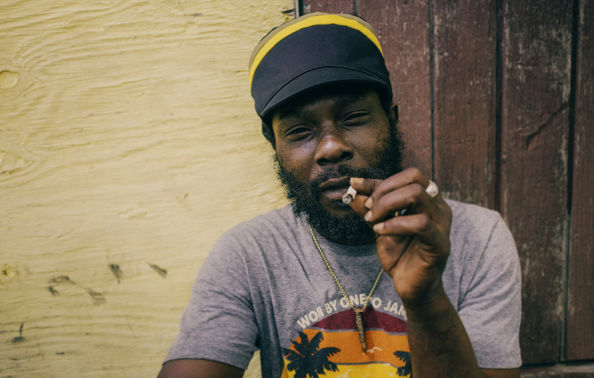 Rastaman in front of a small shop proudly wearing a Jamaican color dreadlocks cap