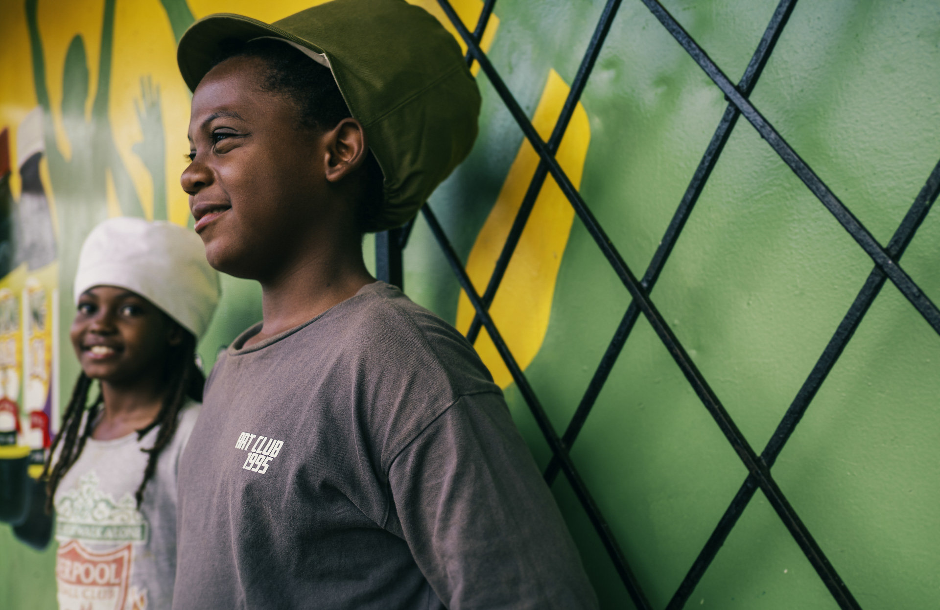 Two children posing with a traditional dreadlocks cap