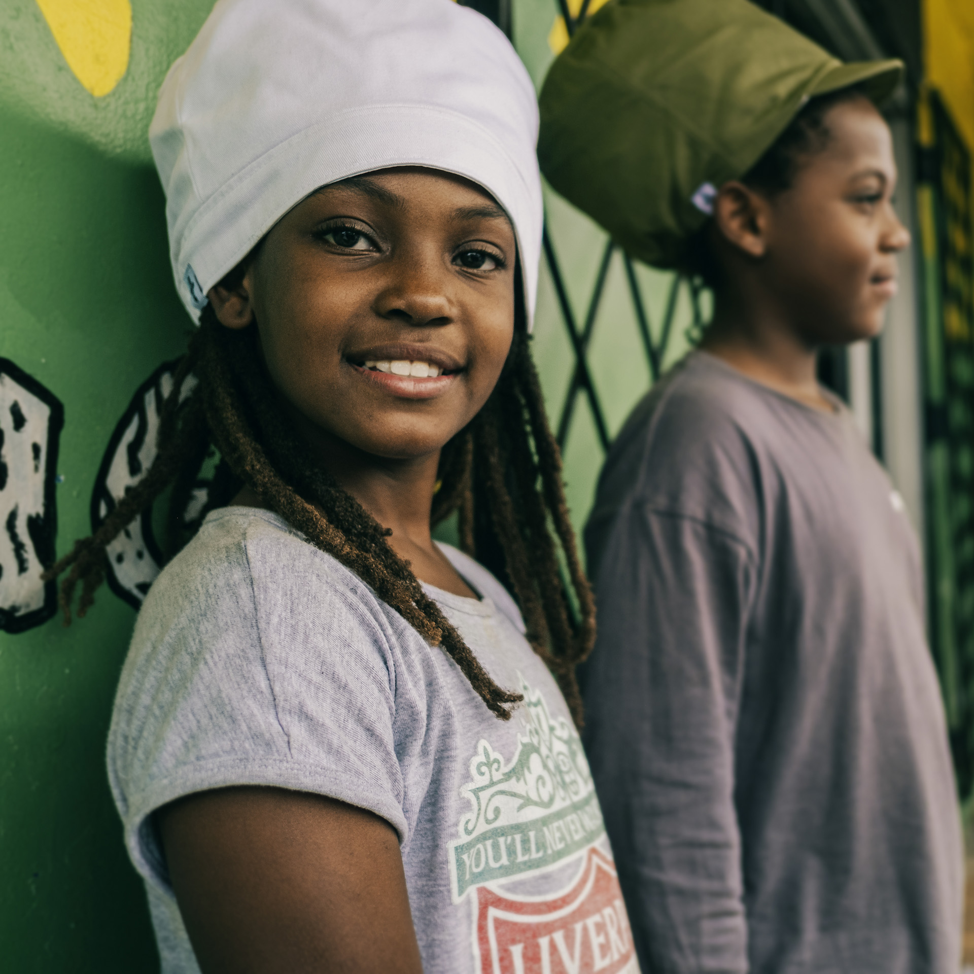 Two children posing with a traditional rasta crown green and white