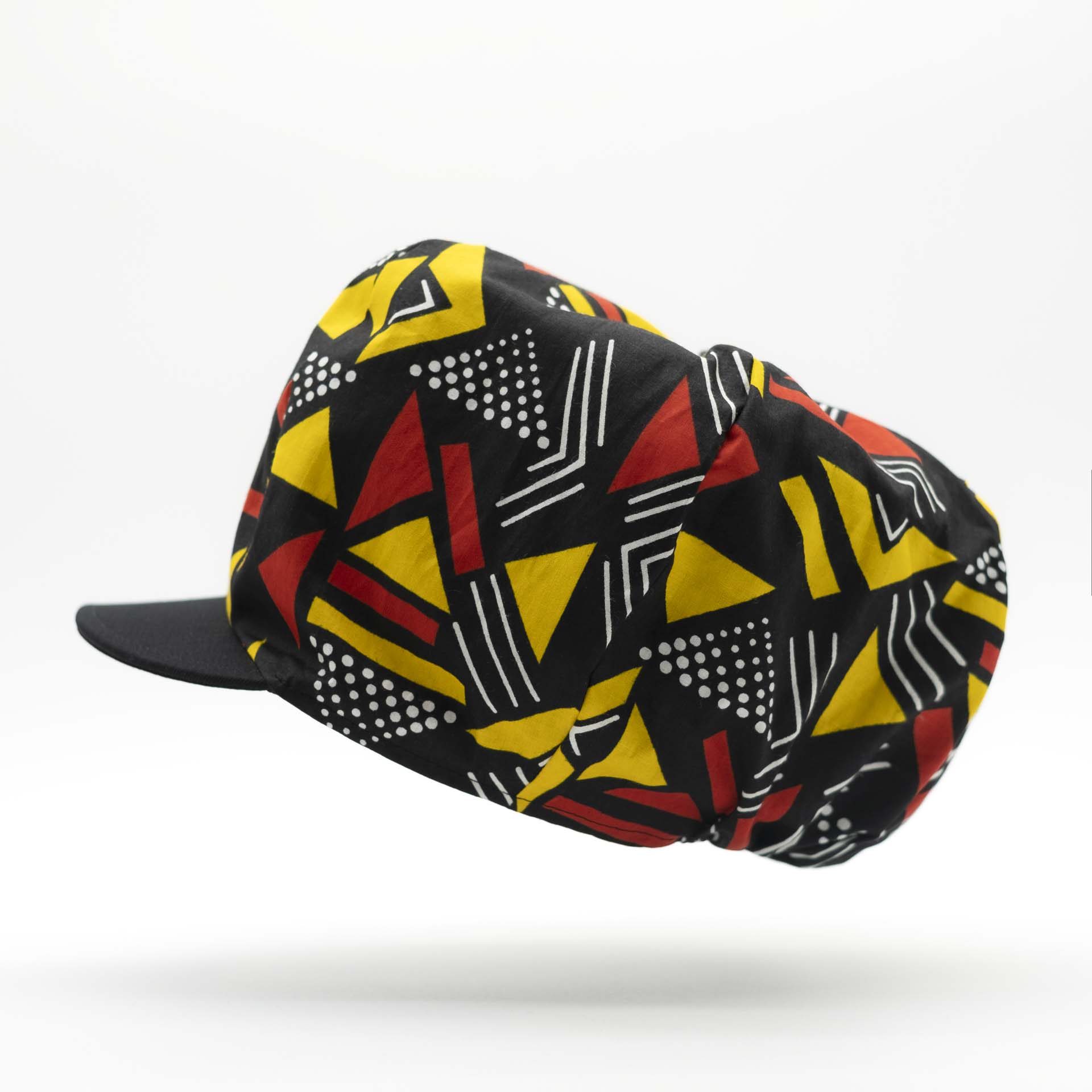 Rasta newsboy cap with dreadlocks with black visor in light wax fabric with colorful red and yellow geometric patterns, black lining