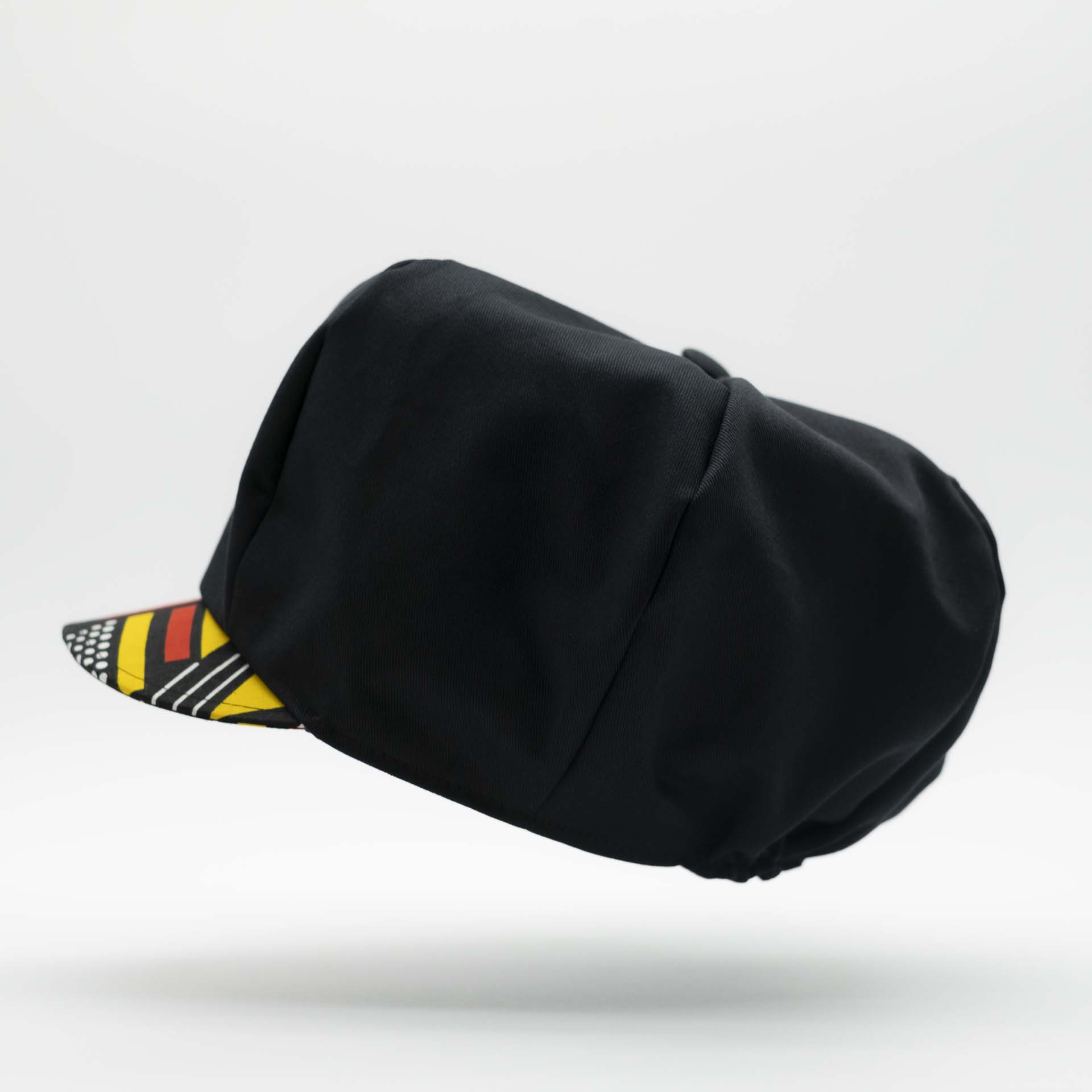 Rasta newsboy cap for dreadlocks in black cotton with wax visor with red and yellow geometric shapes, black lining