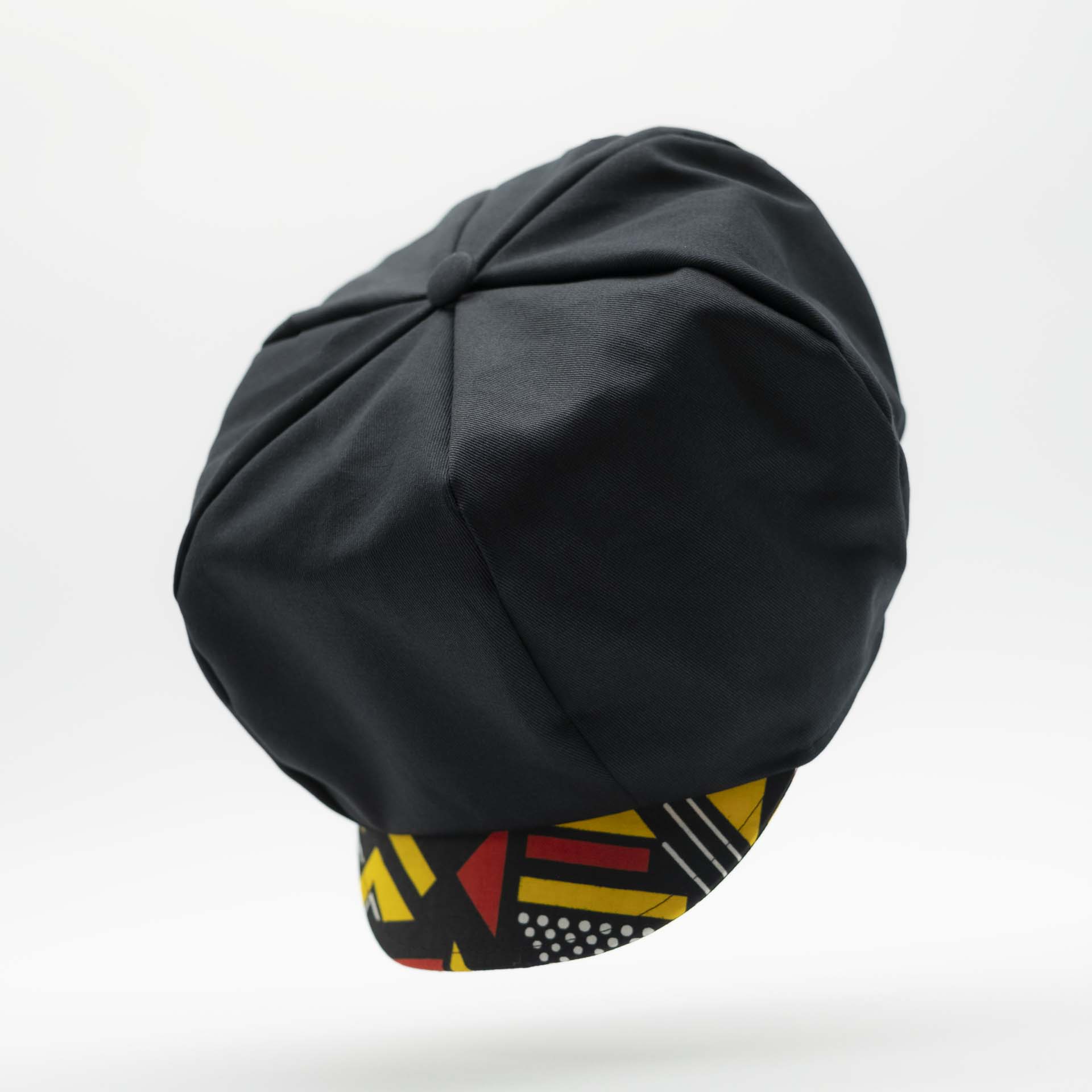 Rasta newsboy cap for dreadlocks in black cotton with wax visor with red and yellow geometric shapes, black lining