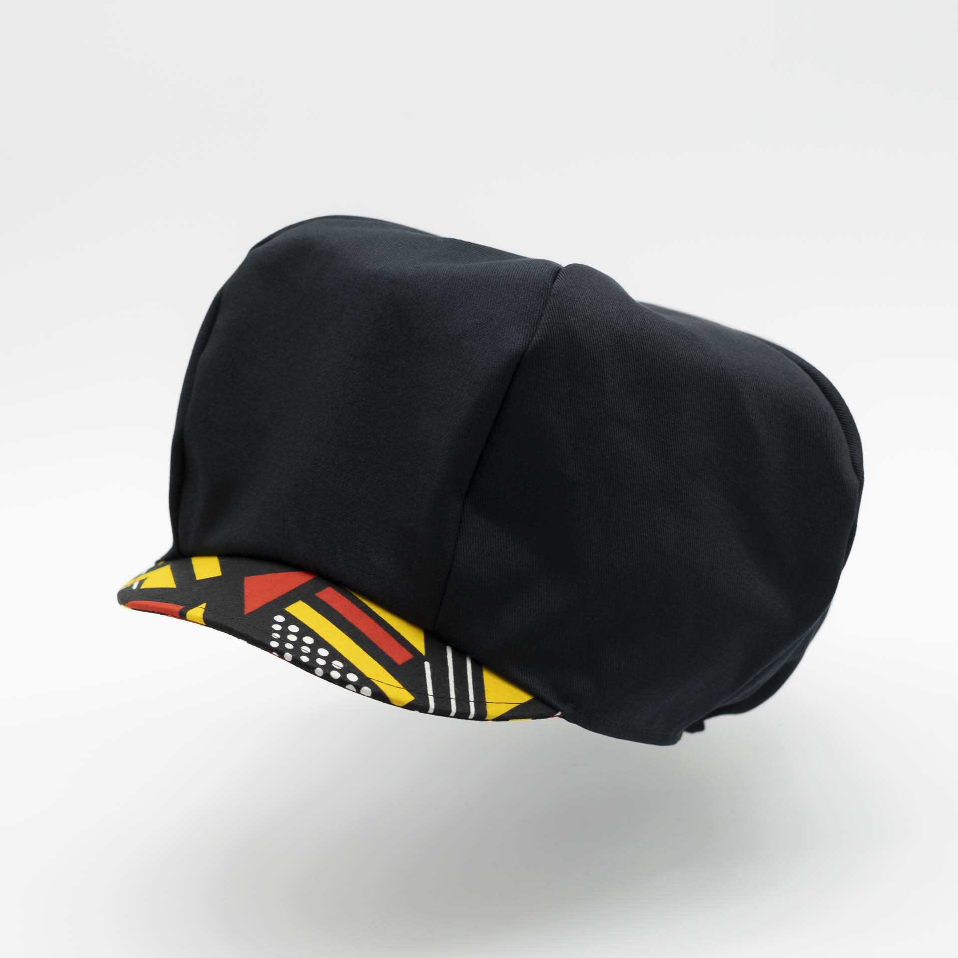 Rasta newsboy cap for dreadlocks in black cotton with wax visor with red and yellow geometric shapes, black lining