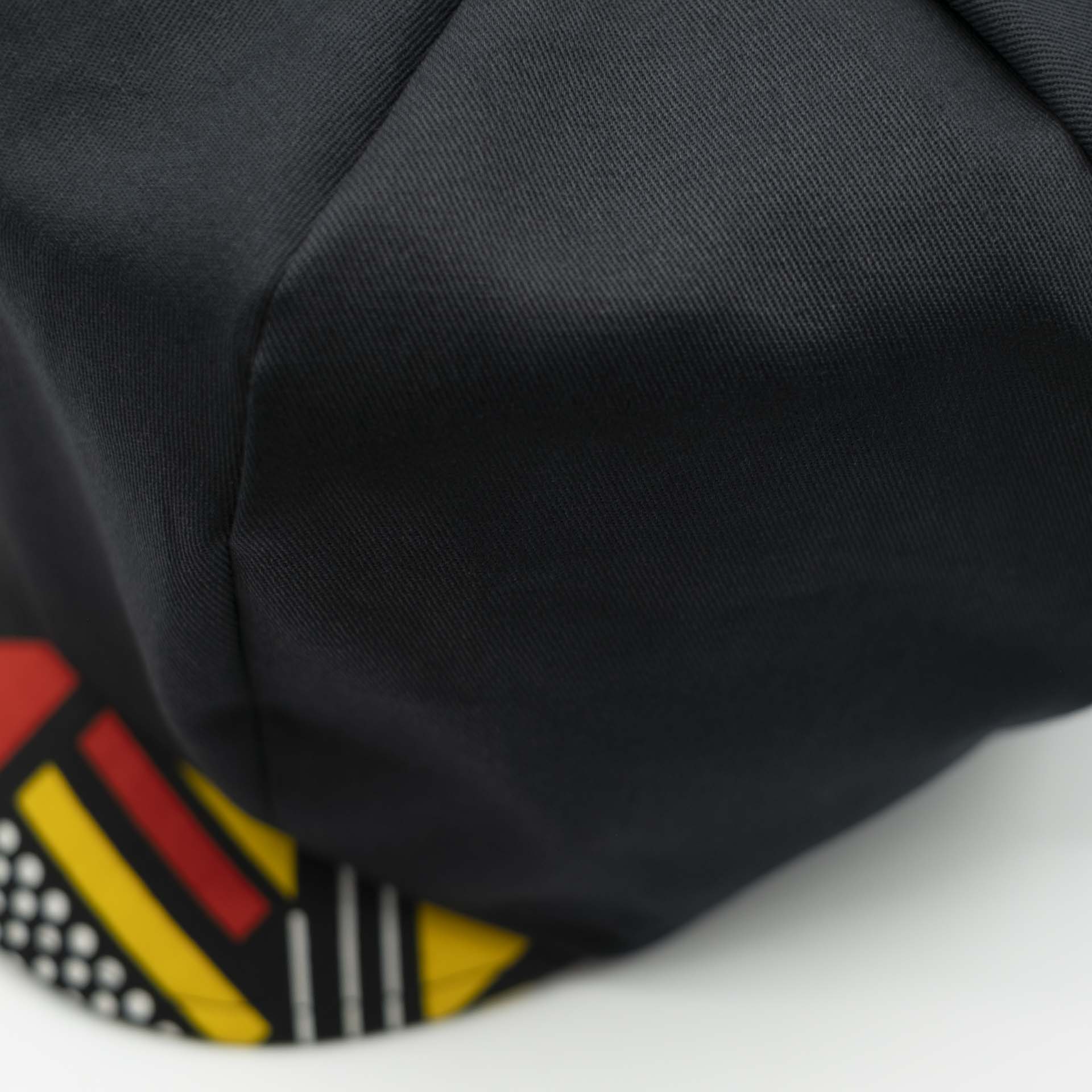 Rasta newsboy cap for dreadlocks in black cotton with wax visor with red and yellow geometric shapes, black lining