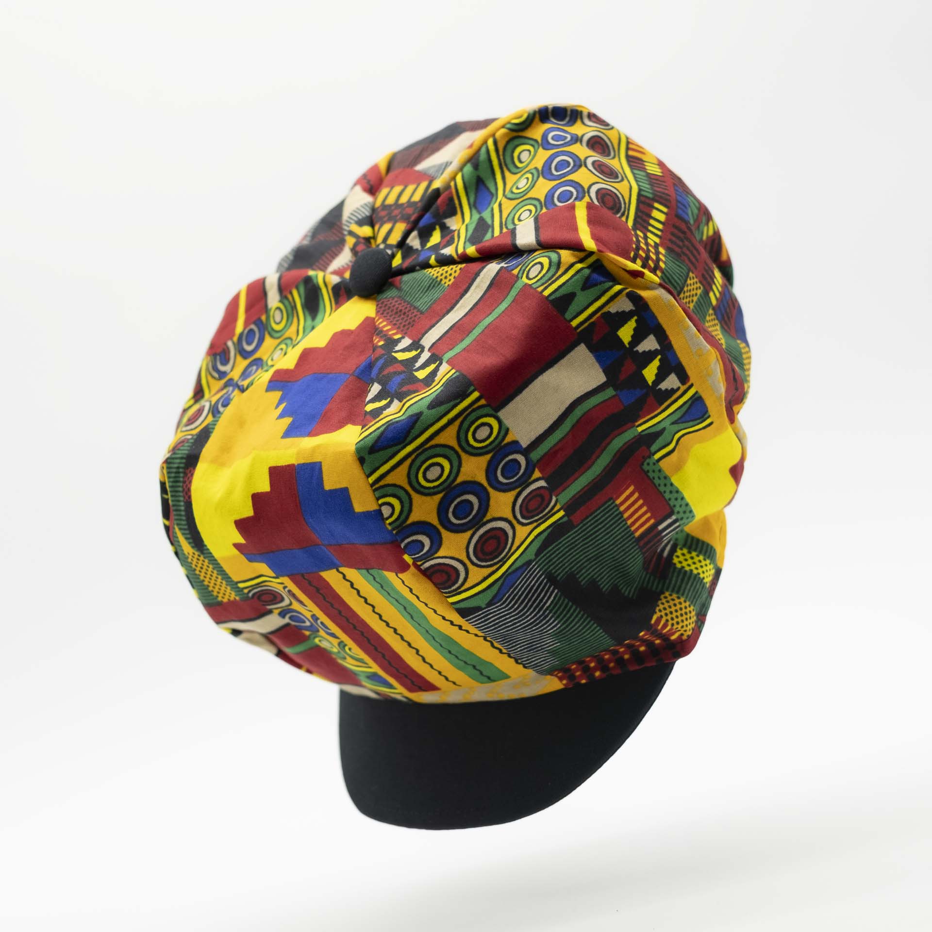 Rasta dreadlocks newsboy cap with black visor in light wax fabric with colorful African patterns, black lining