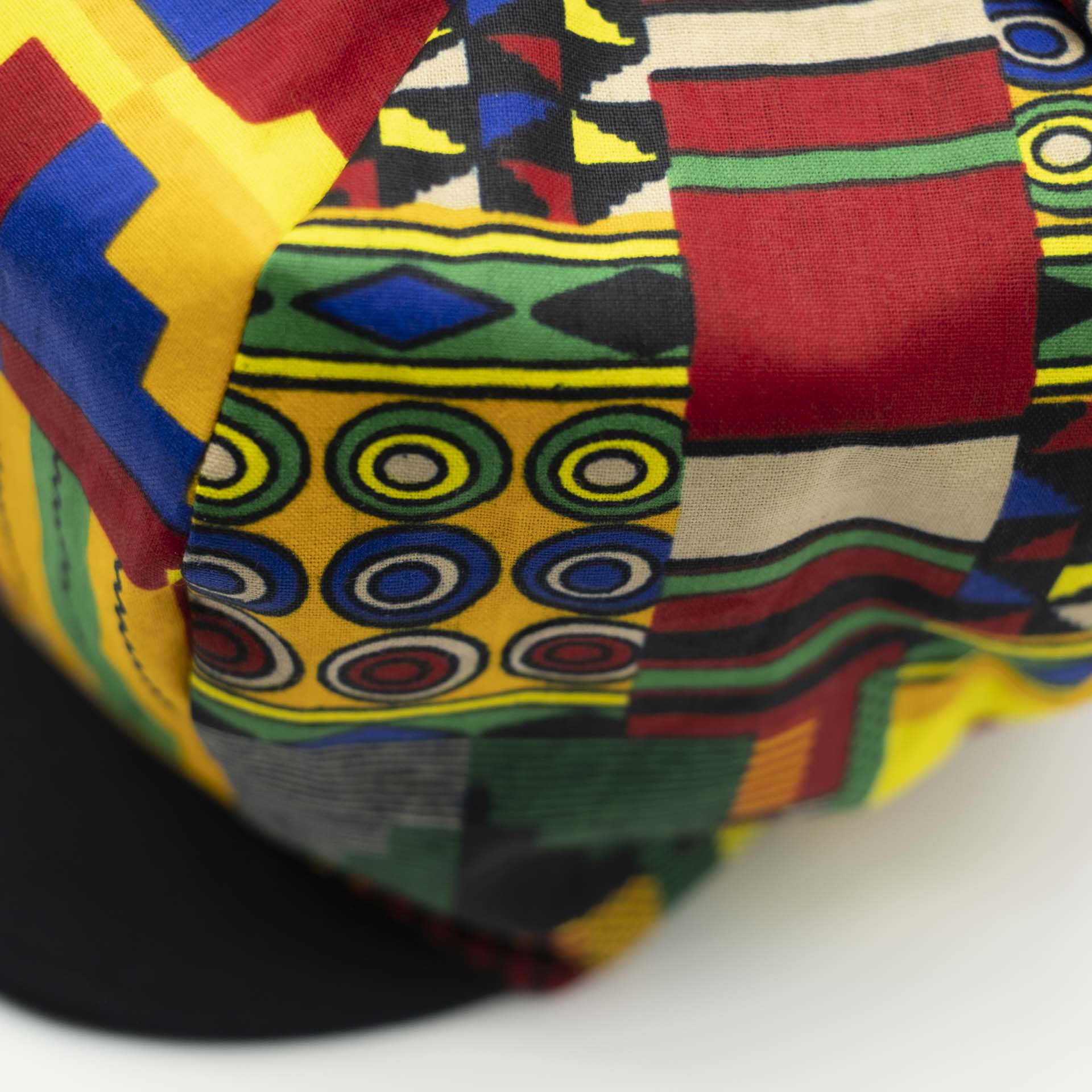 Rasta dreadlocks newsboy cap with black visor in light wax fabric with colorful African patterns, black lining