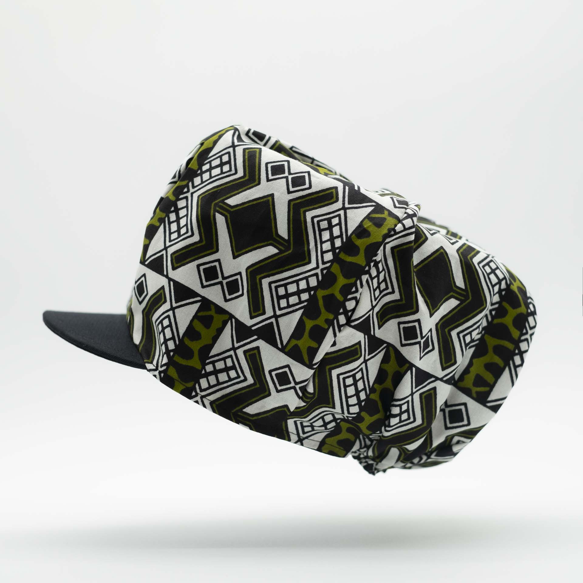 Rasta dreadlocks newsboy cap with black visor in light wax fabric with black African ethnic patterns on a white background with black lining