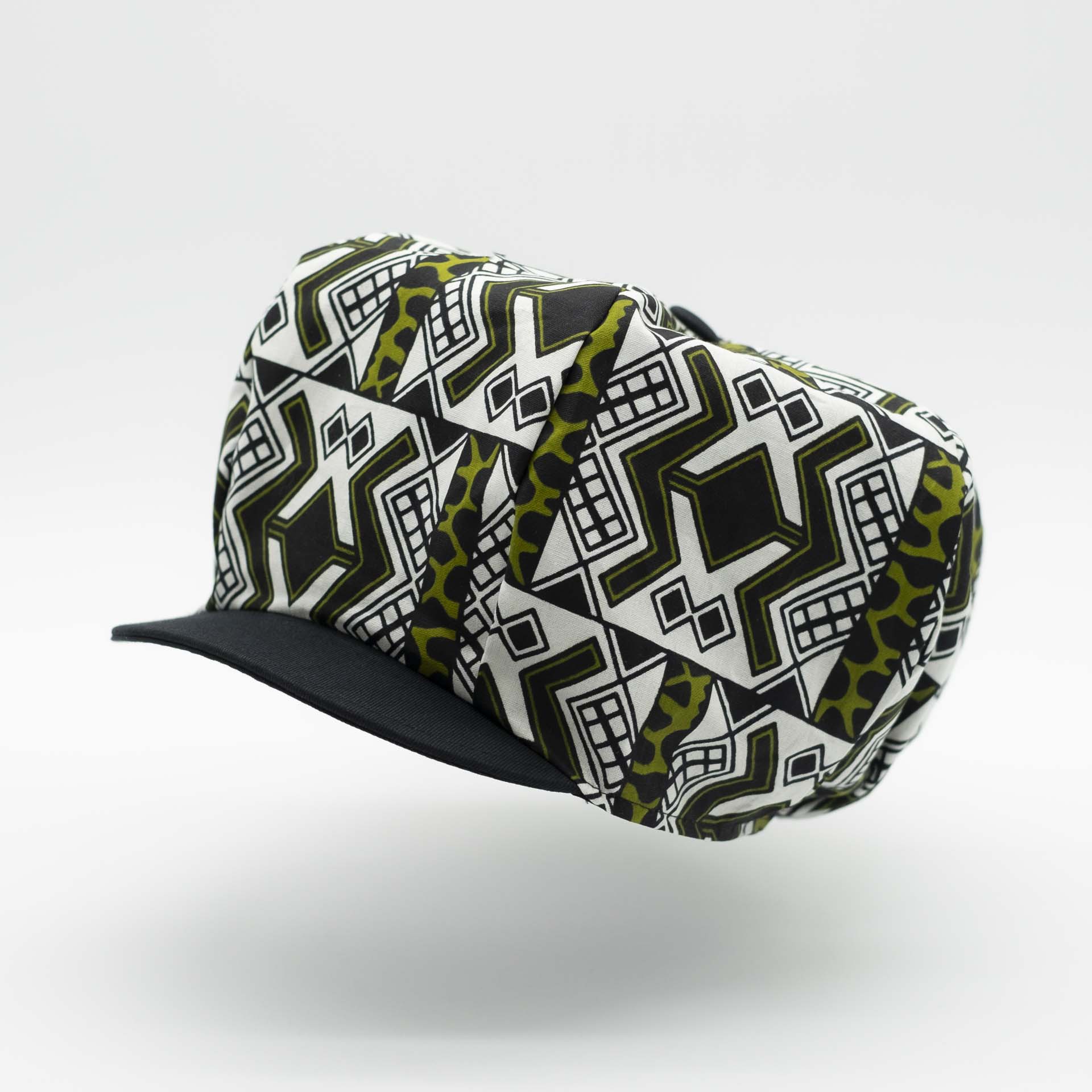 Rasta dreadlocks newsboy cap with black visor in light wax fabric with black African ethnic patterns on a white background with black lining