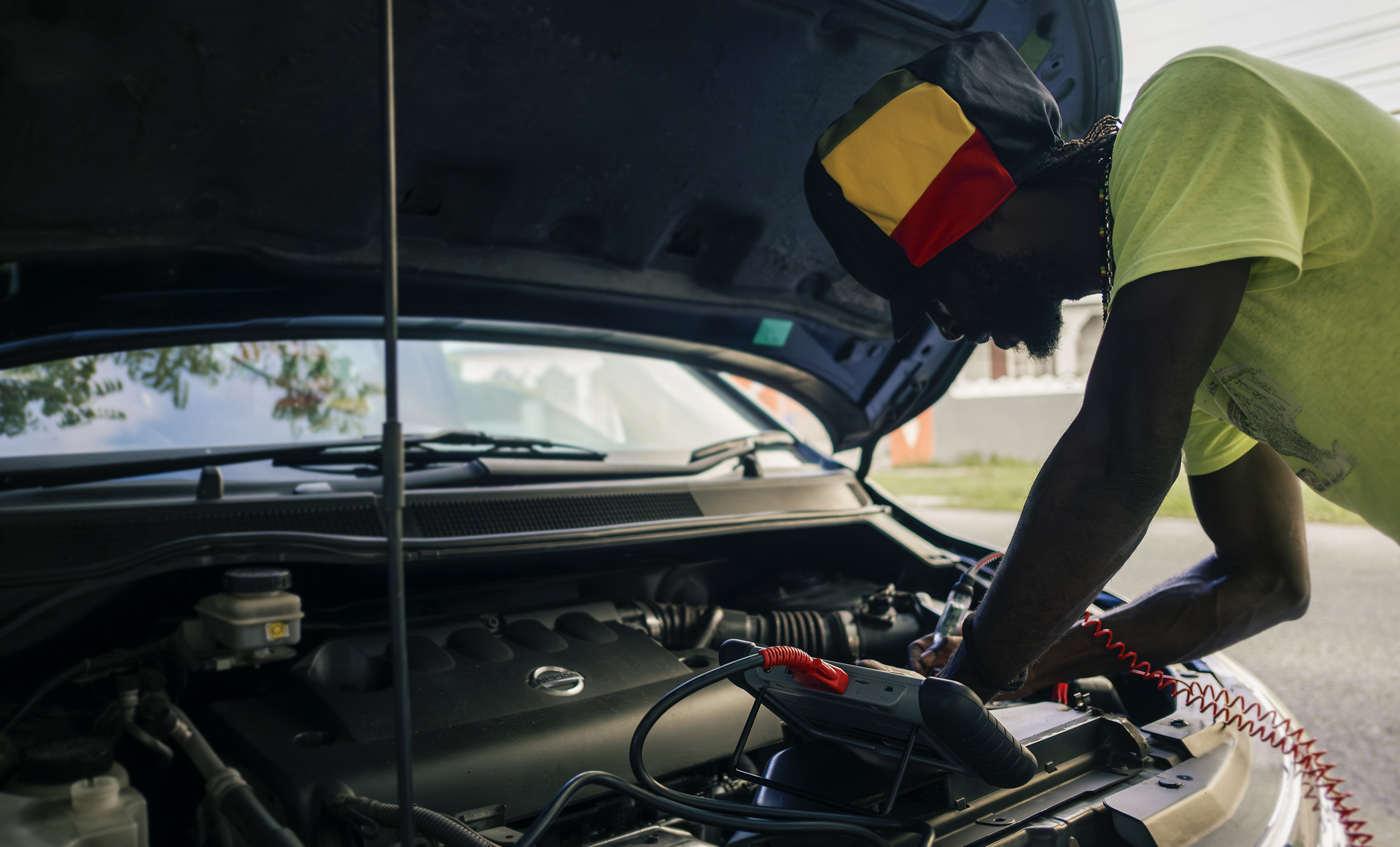 Rastaman fixing a car in Kingston with a black dreadlocks Nation hat from the Rocksteady collection