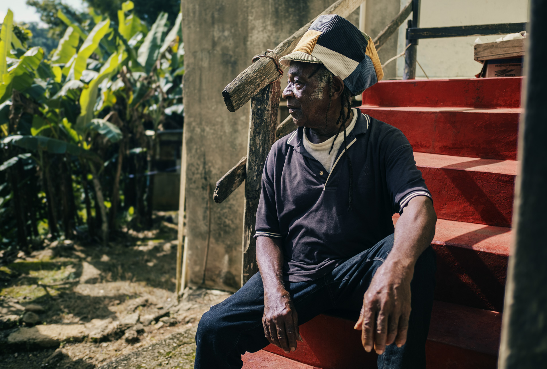 Elder with a Dreadlocks hat in his yard