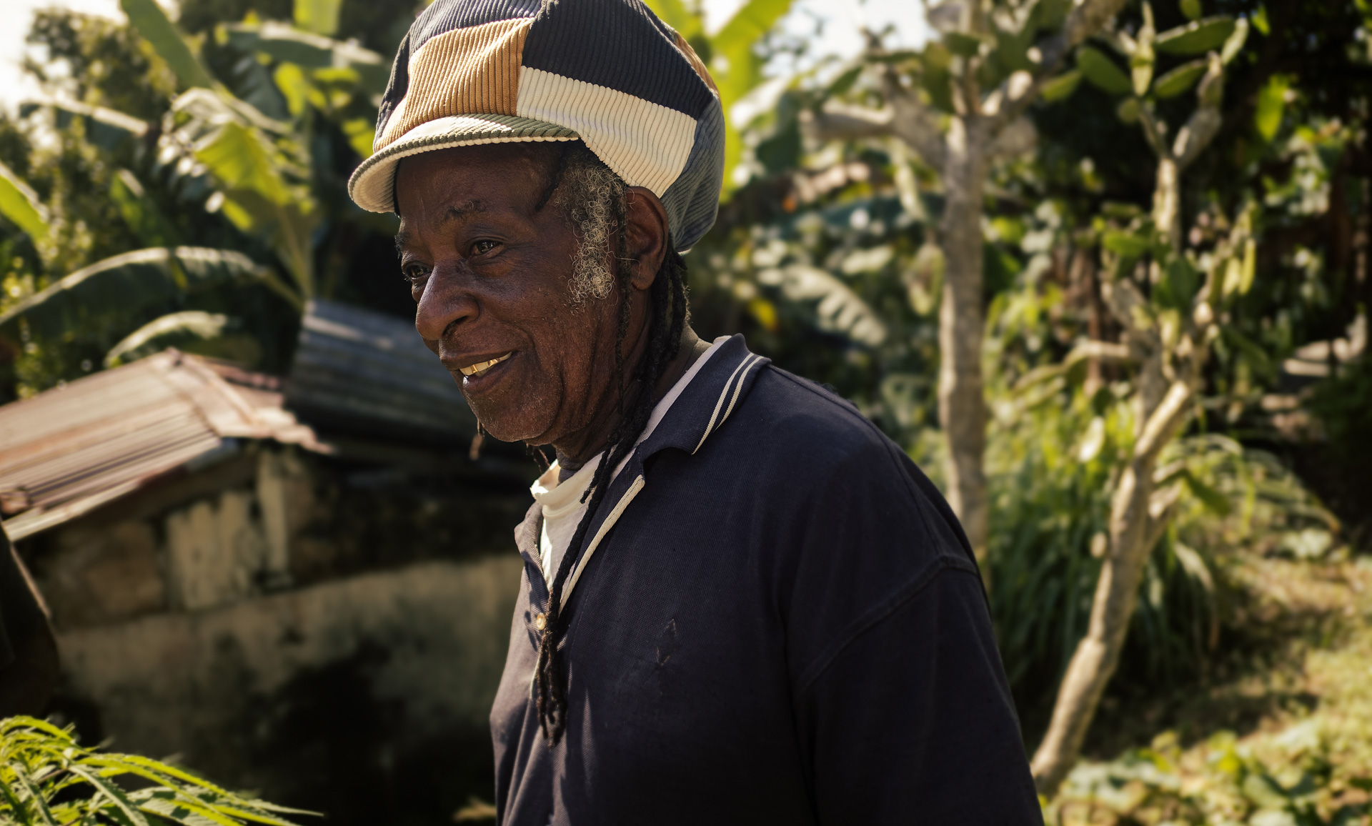 Ancien dans son yard portant une casquette rasta pour dreadlocks en velours