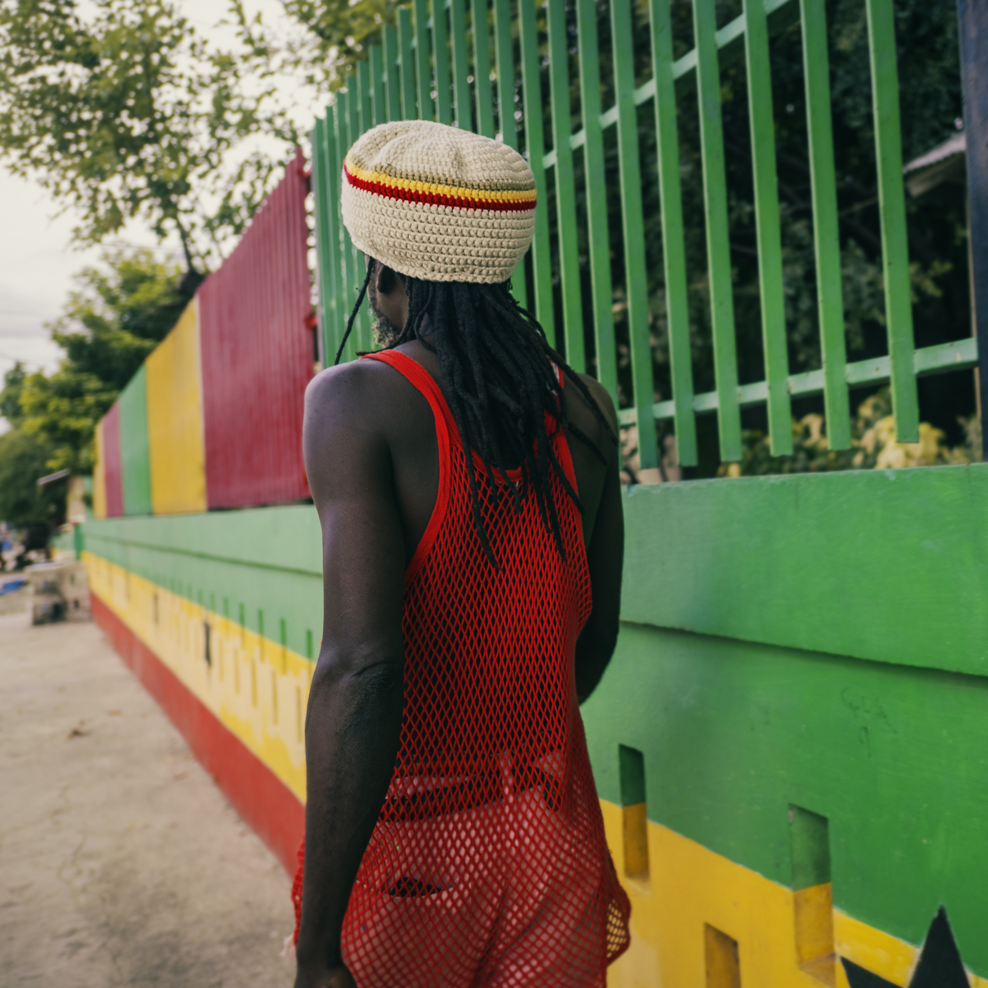 A Rastaman walking in the street of Cultural Yard Trenchtown Jamaica and wearing a Dreadlocks crown, in beige wool and Ethiopian colors