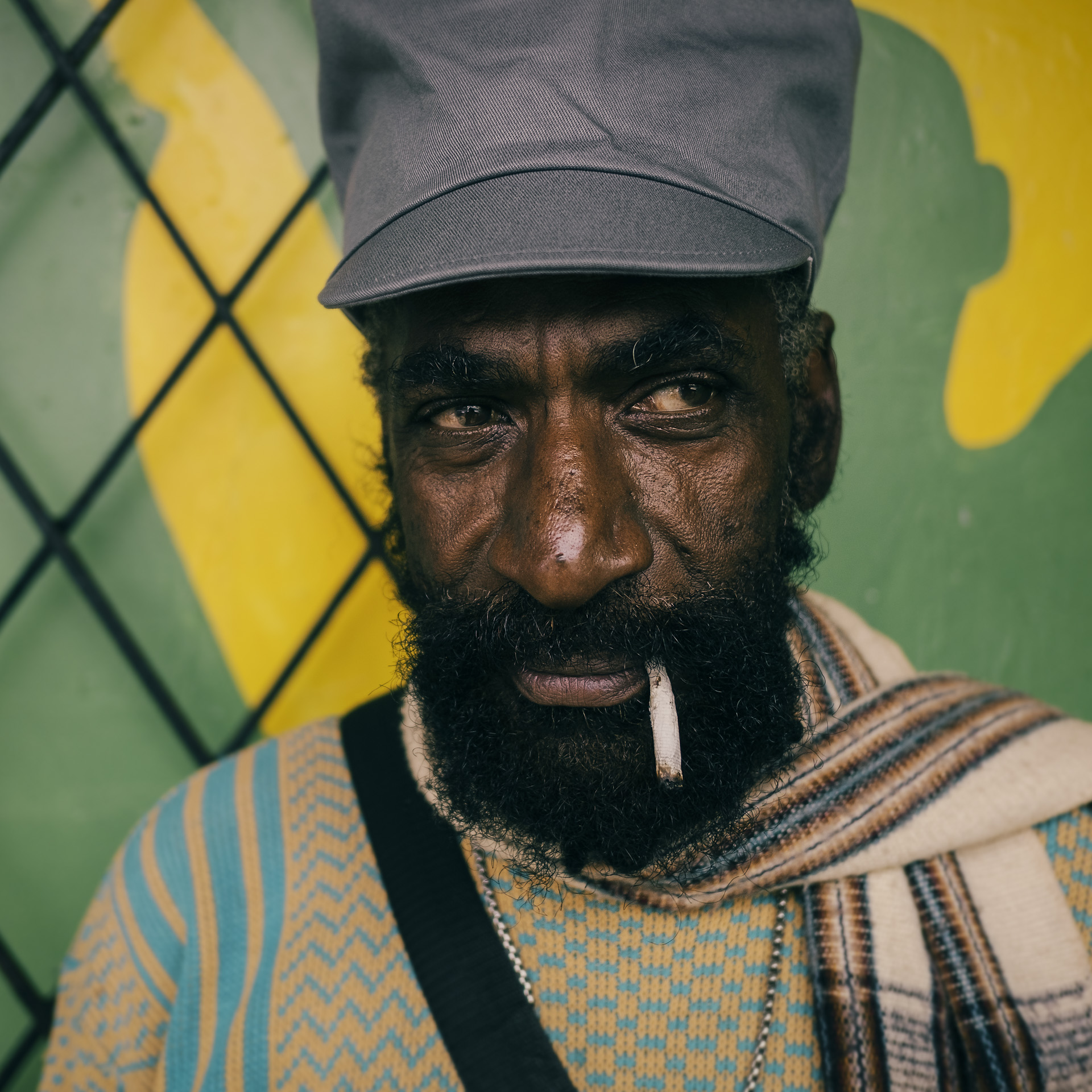 Jamaican Rasta wearing grey dreadlocks cap and smoking a spliff in the street